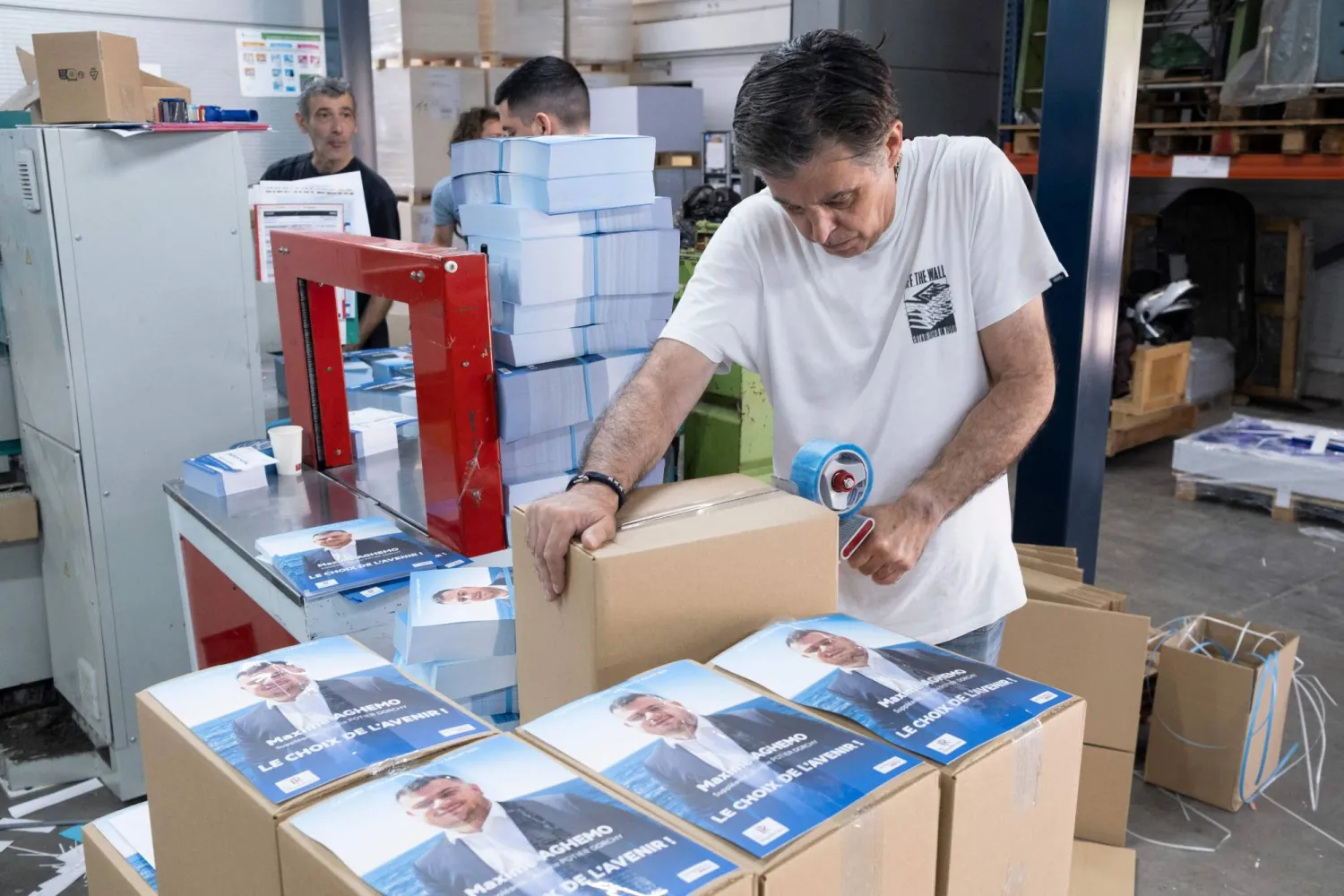 موظف في إحدى المطابع يتحقق من ملصقات ومنشورات الحملة المطبوعة للانتخابات البرلمانية الفرنسية المقبلة (أ.ف.ب)