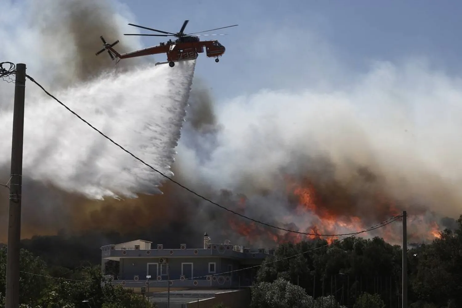 A firefighting helicopter drops water during a fire that broke out in Varis - Koropiou, eastern Attica, Greece, 19 June 2024. (EPA)