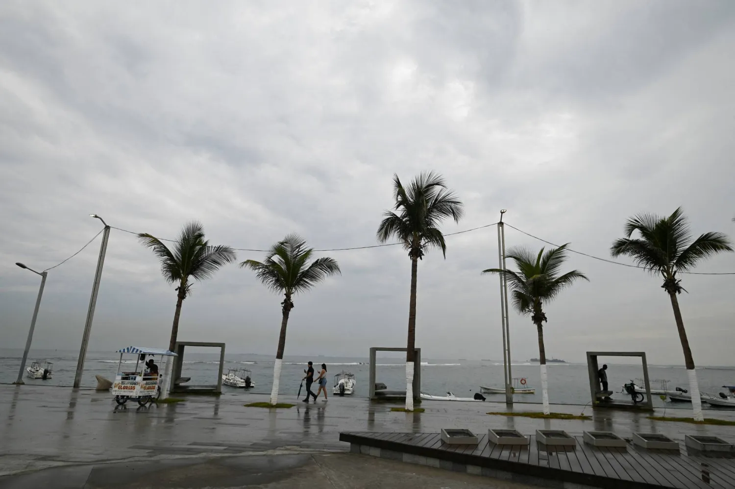 People walk on a pier as dark clouds caused by Tropical Storm Alberto are seen on the horizon, in Veracruz, Mexico June 19, 2024. REUTERS/Yahir Ceballos