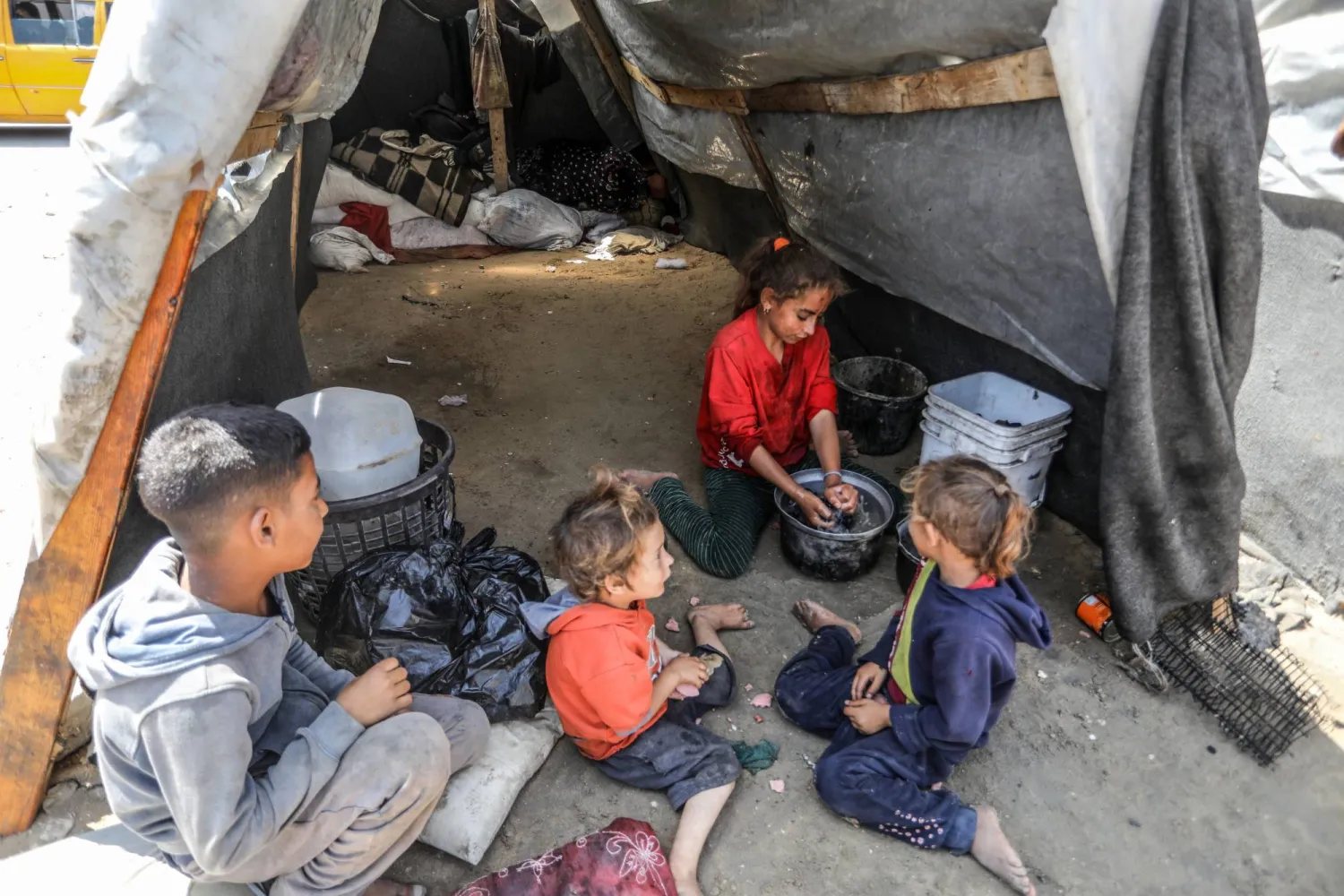 أطفال فلسطينيون نزحوا مع عائلتهم في خيمة في دير البلح الخميس (د.ب.أ)