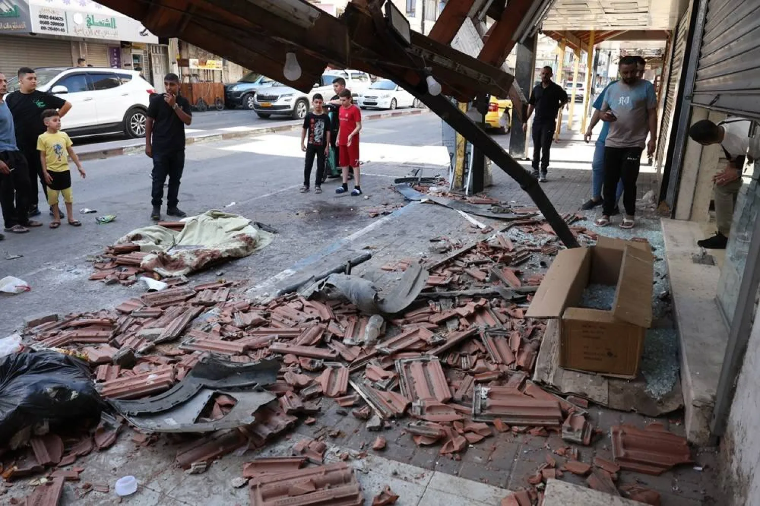Palestinians inspect the damage at the site where two Palestinians were killed during an Israeli operation in the West Bank city of Qalqilia, 21 June 2024. (EPA) 
