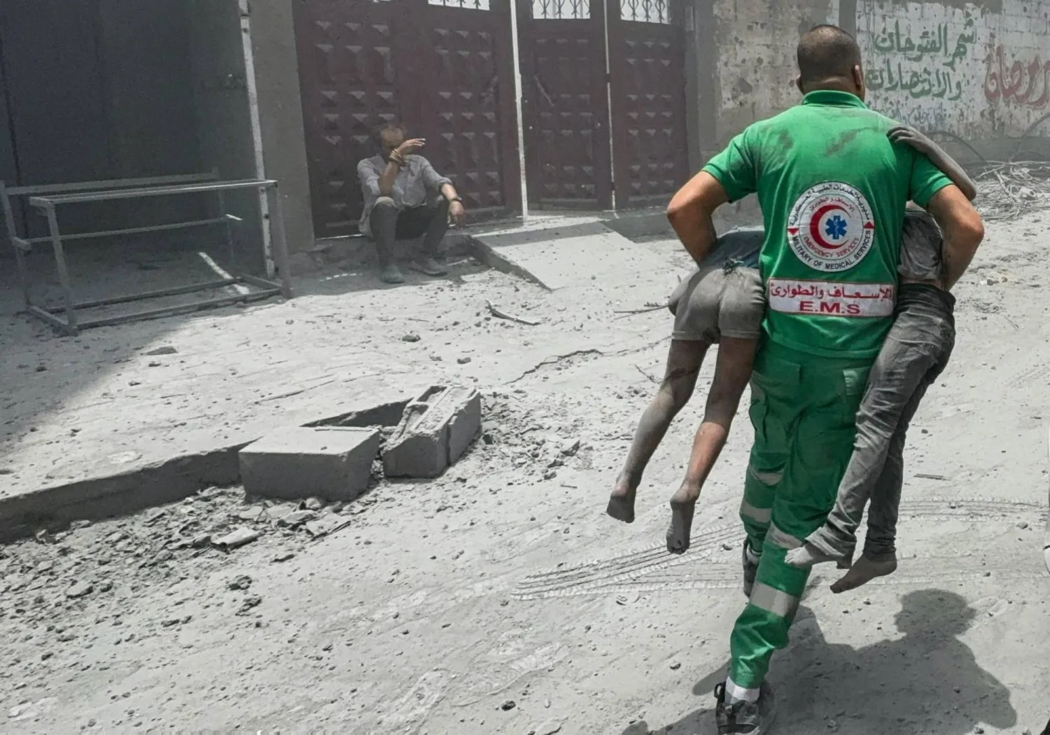 İsrail'in dün (cumartesi) Gazze şehrindeki evleri hedef alan saldırısının gerçekleştiği yerde iki Filistinli çocuğu taşıyan bir ambulans görevlisi (Reuters)