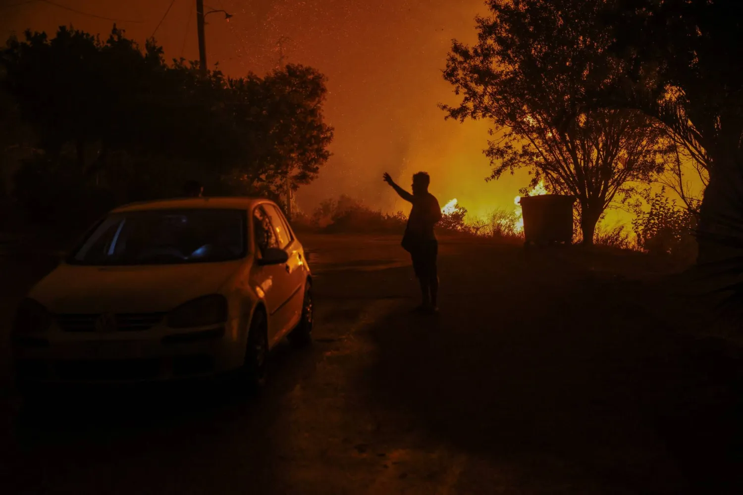 A local resident stands next to a wildfire burning in the village of Latas, in southern Greece, June 21, 2024. REUTERS/Giorgos Moutafis