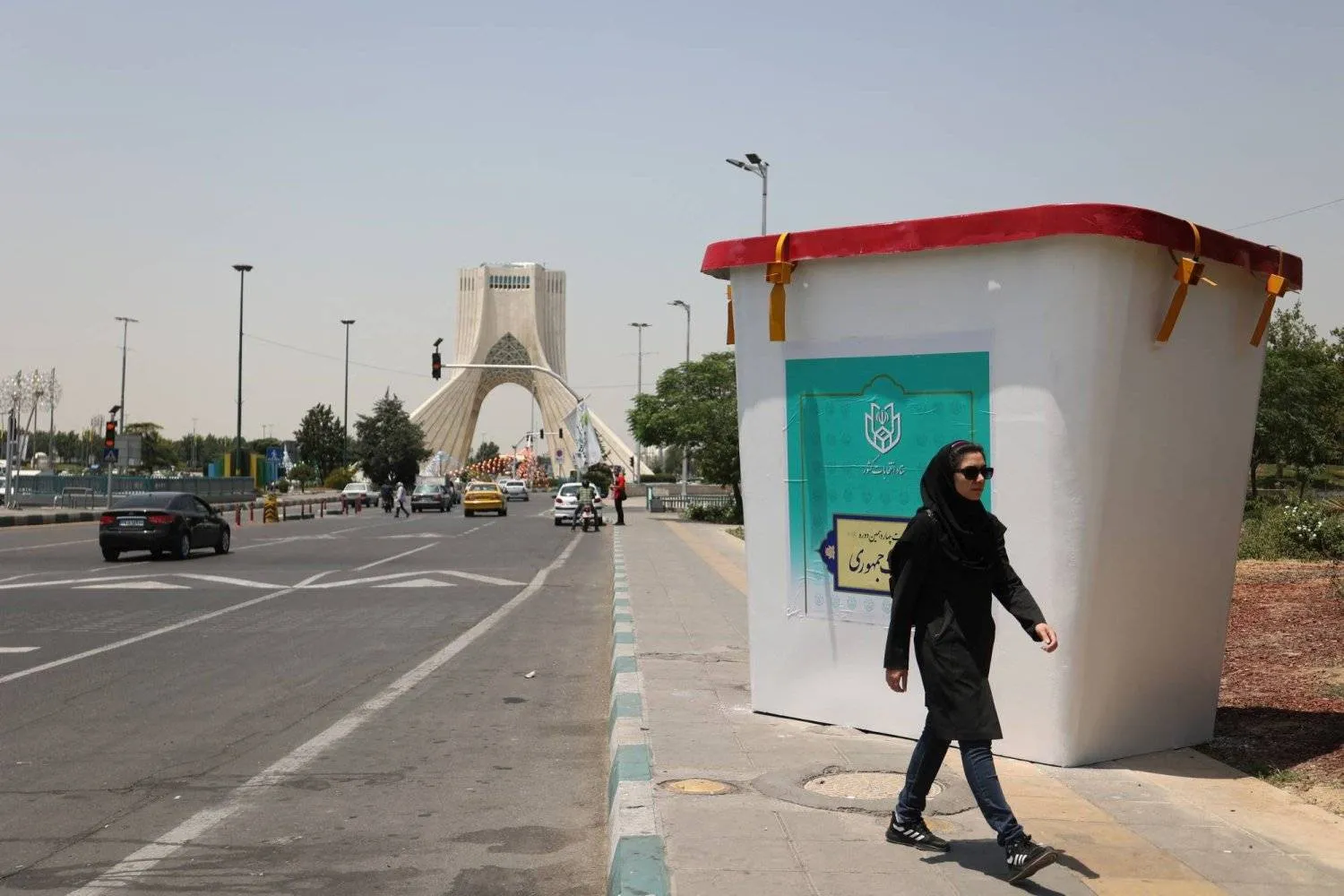 A woman walks past a symbolic ballot box for the presidential election in a street in Tehran, Iran June 22, 2024. Majid Asgaripour/WANA (West Asia News Agency) via Reuters 