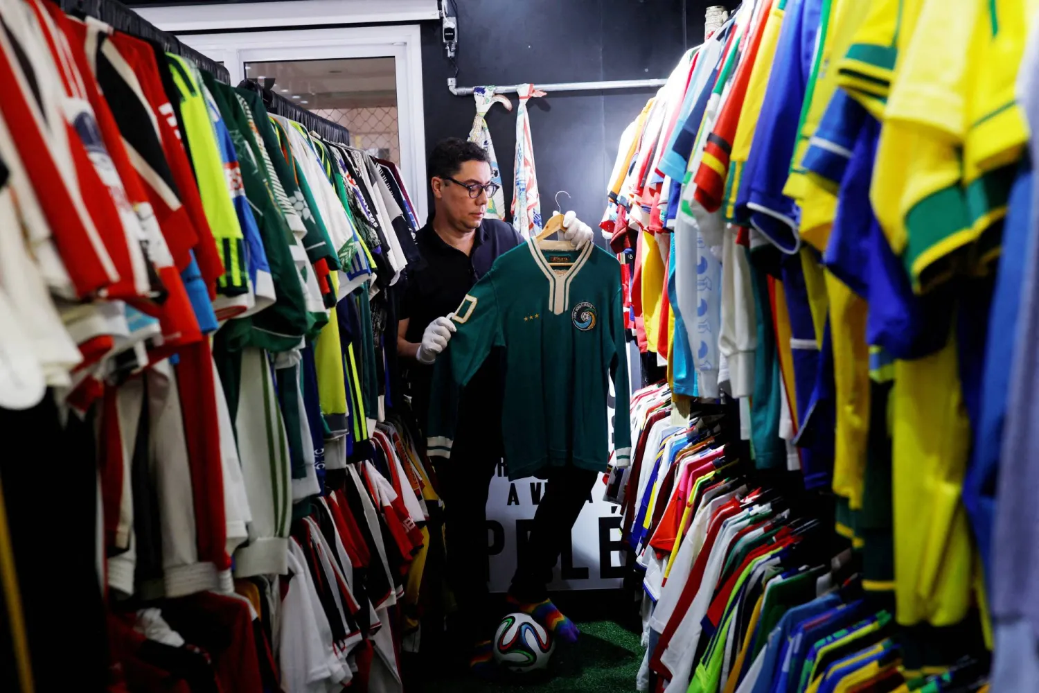 البرازيلي كاسيو برانداو يستعرض قميصين ارتداهما أسطورة البرازيل الراحل بيليه (رويترز)