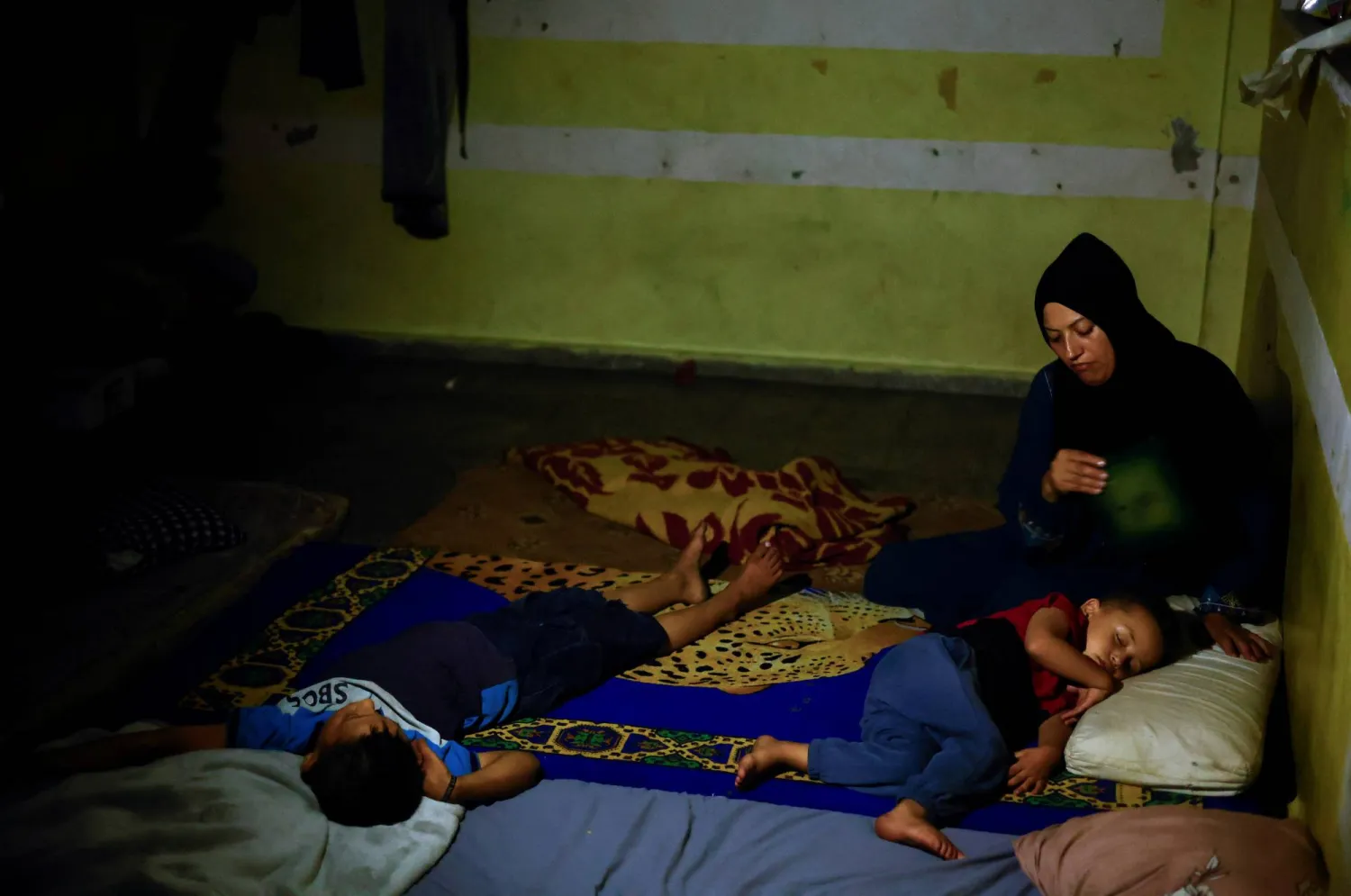 أمل نصير بمعية أطفالها داخل إحدى مدارس الأمم المتحدة في خان يونس 25 يونيو 2024 (رويترز)