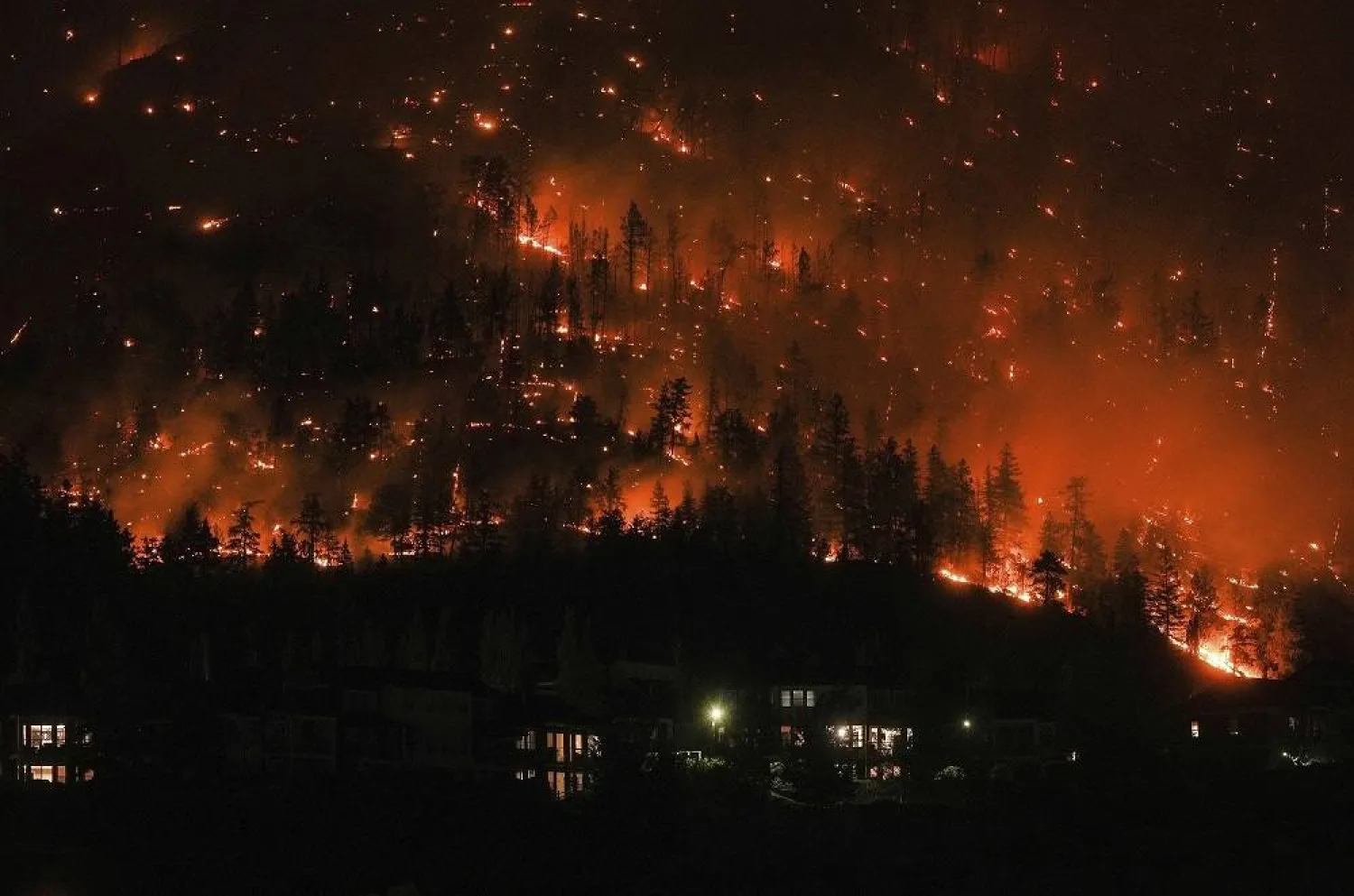 The McDougall Creek wildfire burns on the mountainside above houses in West Kelowna, British Columbia, Aug. 18, 2023. (Darryl Dyck/The Canadian Press via AP, File)
