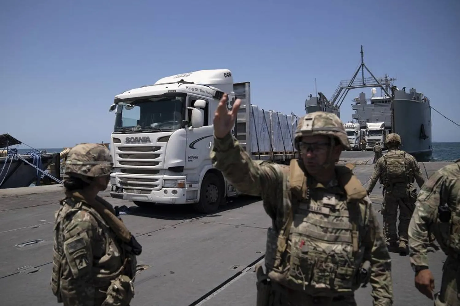  A US Army soldier gestures as trucks loaded with humanitarian aid arrive at the US-built floating pier Trident before reaching the beach on the coast of the Gaza Strip, Tuesday, June 25, 2024. (AP)