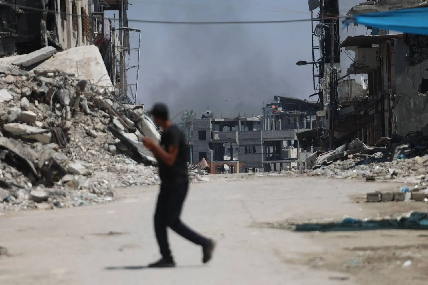 Gazze Şehri'ndeki Şucaiyye mahallesinde İsrail bombardımanının olduğu bölgeden geçen bir Filistinli (AFP)