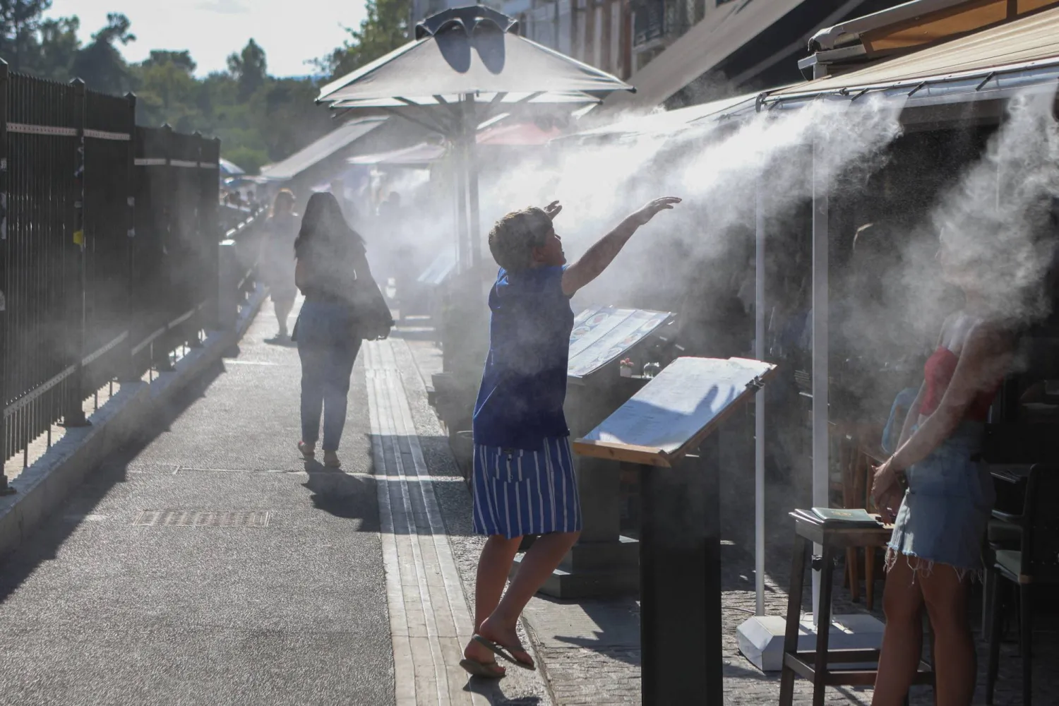 A boy cools himself from the misting system of a cafe in Athens, Greece, June 28, 2024. REUTERS/Elias Marcou