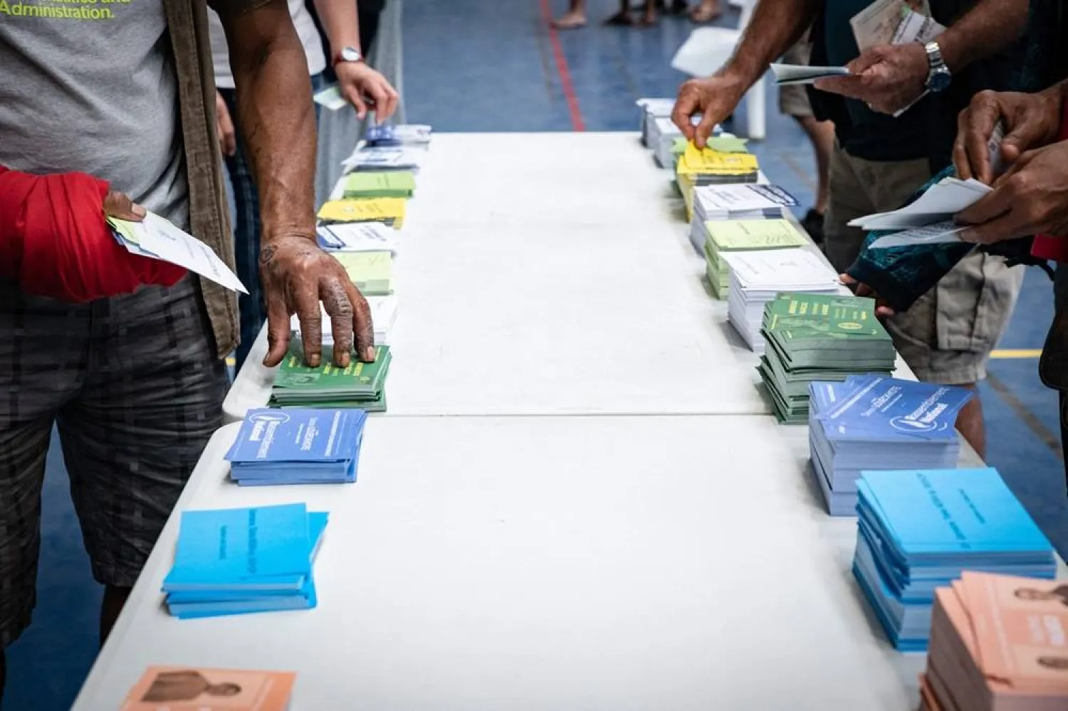 People collect ballots at a polling station inside the Anse Vata sports hall to vote in the first round of France's crunch legislative elections in Noumea, in France's Pacific territory of New Caledonia, on June 30, 2024. (AFP)