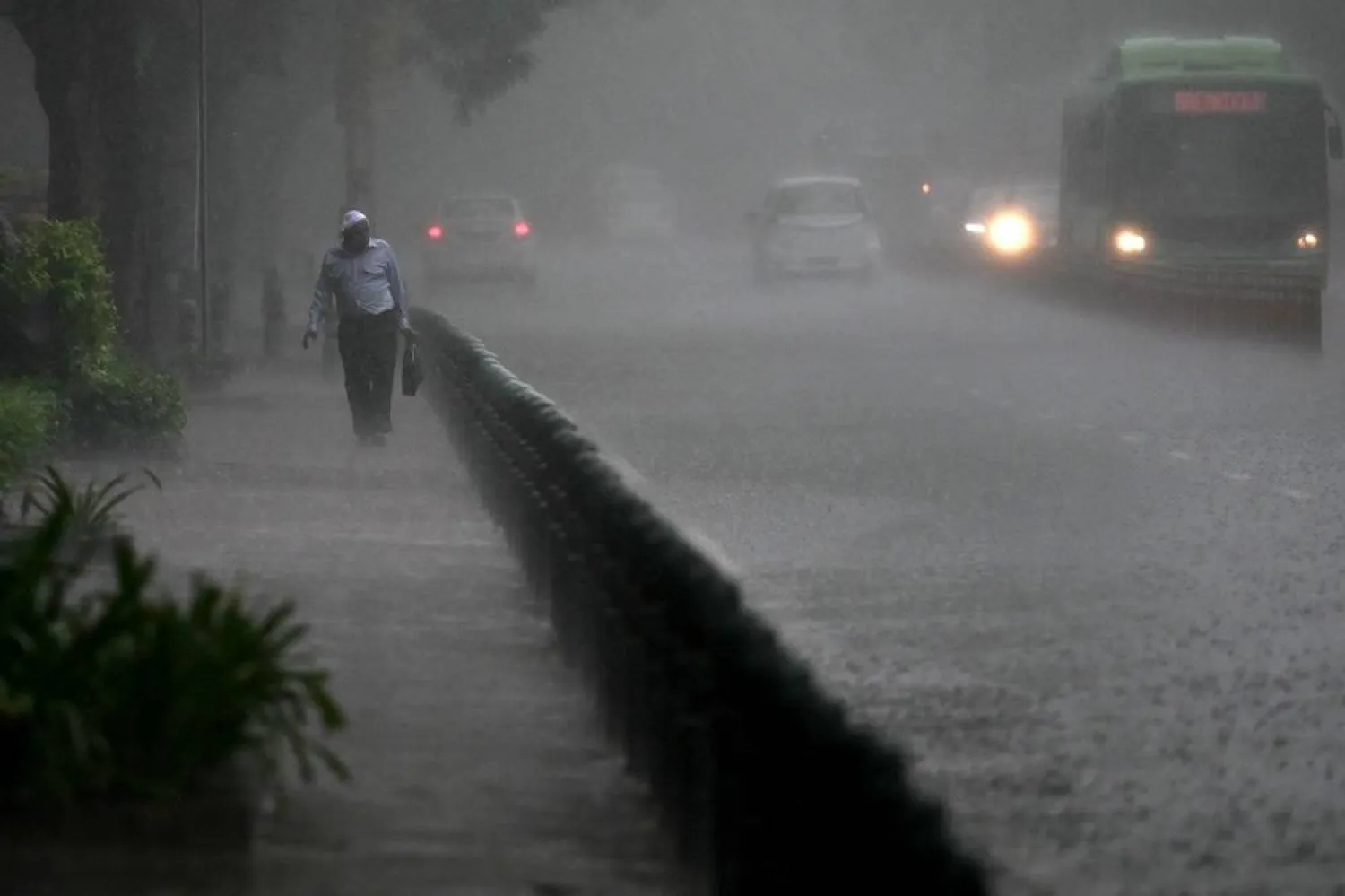 A man walks along a road amid heavy rainfall in New Delhi on June 29, 2024. (AFP)