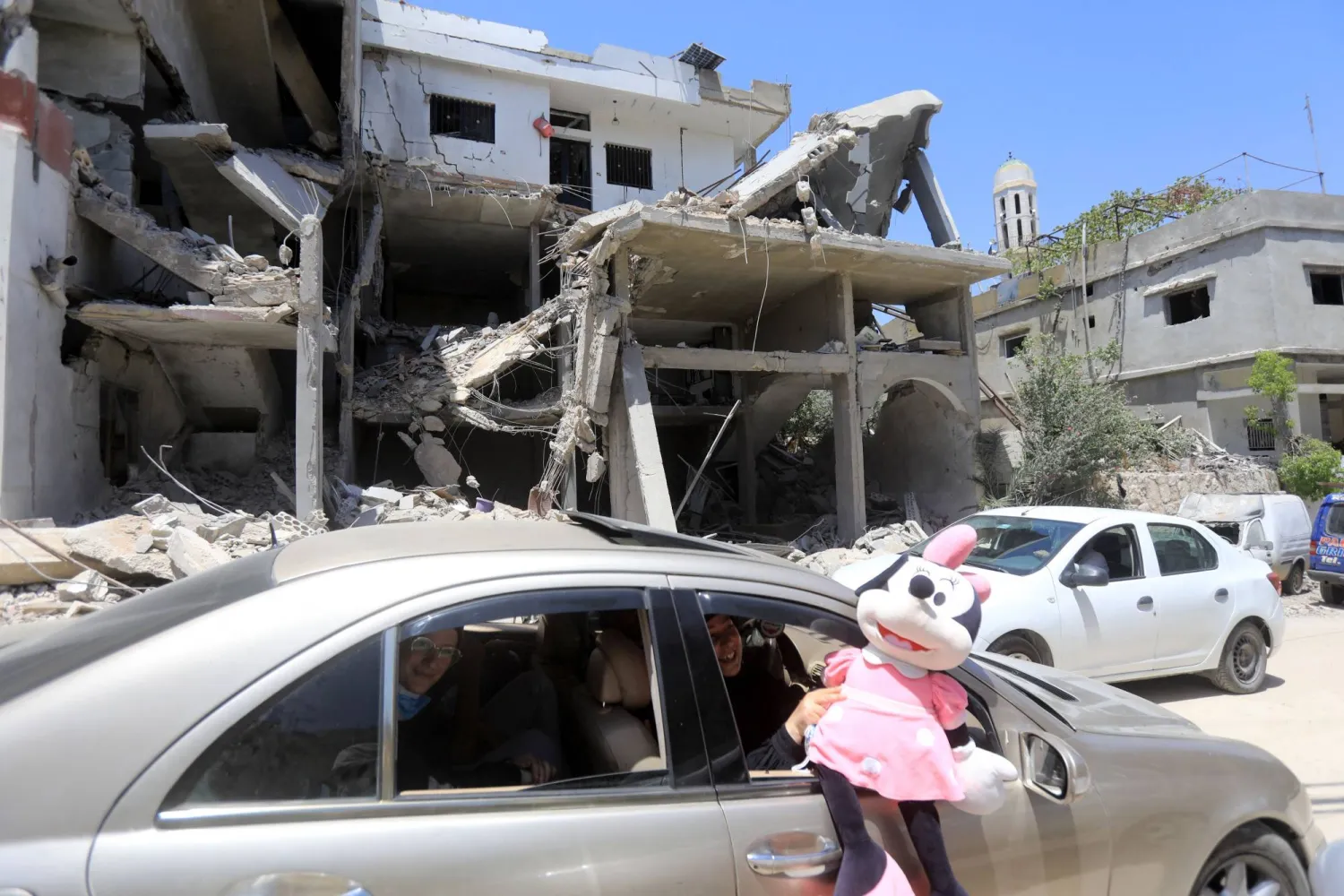 امرأة تحمل دمية خلال عبورها أمام منزل دمره قصف إسرائيلي في بلدة عيتا الشعب بجنوب لبنان (أ.ف.ب)