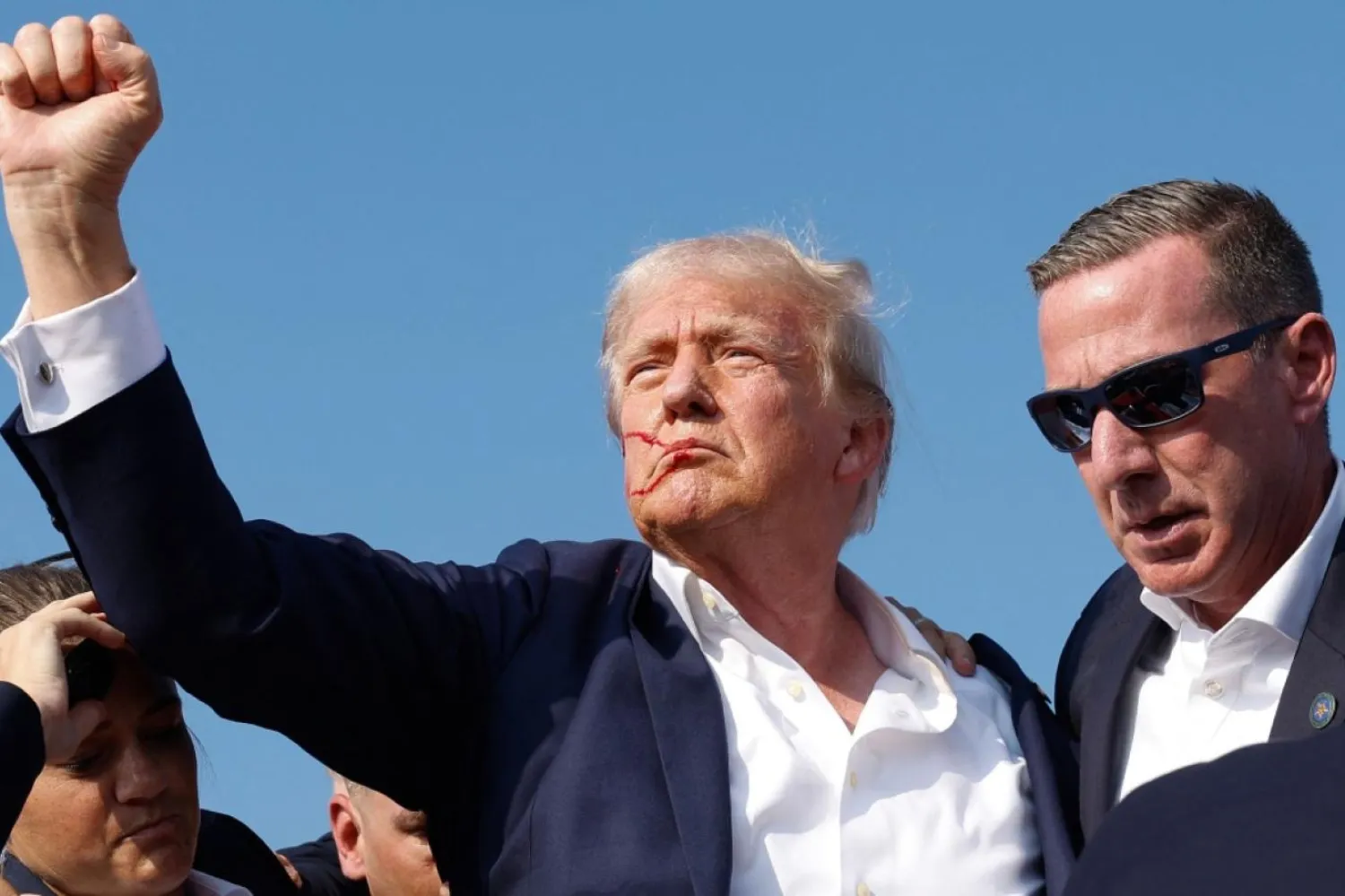 Trump'ın suikast girişimi sonrası miting kürsüsünde verdiği poz ikonik karelerden birine dönüştü (AFP)