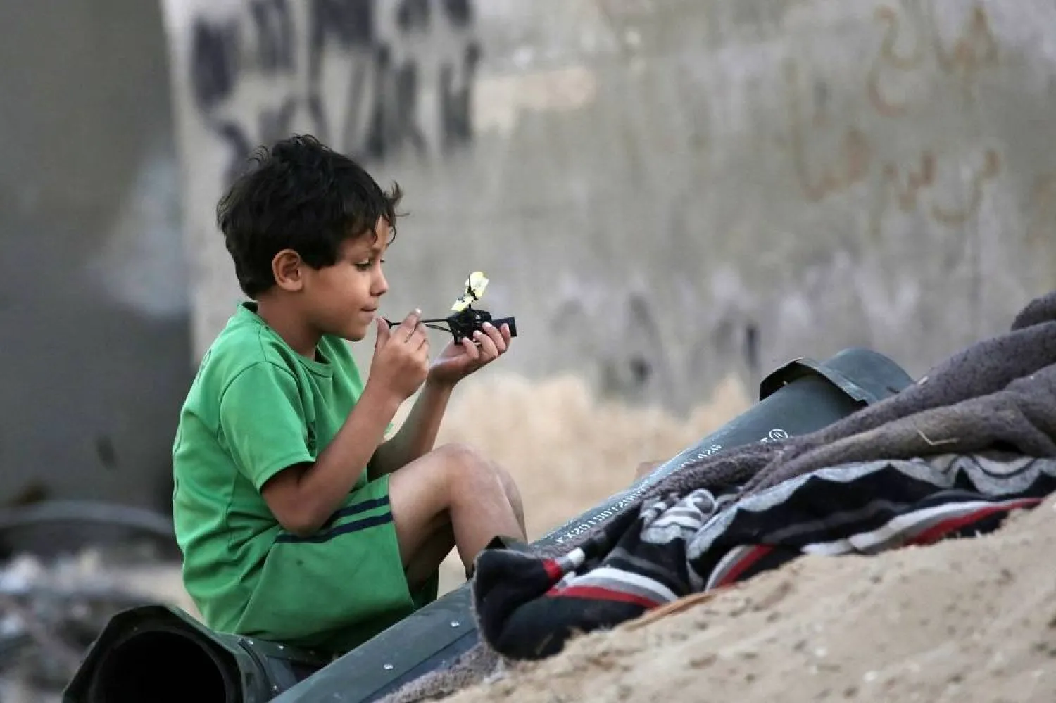 A Palestinian child plays next to empty ammunition containers in Khan Younis in the southern Gaza Strip on May 16, 2024, amid the ongoing conflict between Israel and Hamas. (AFP)