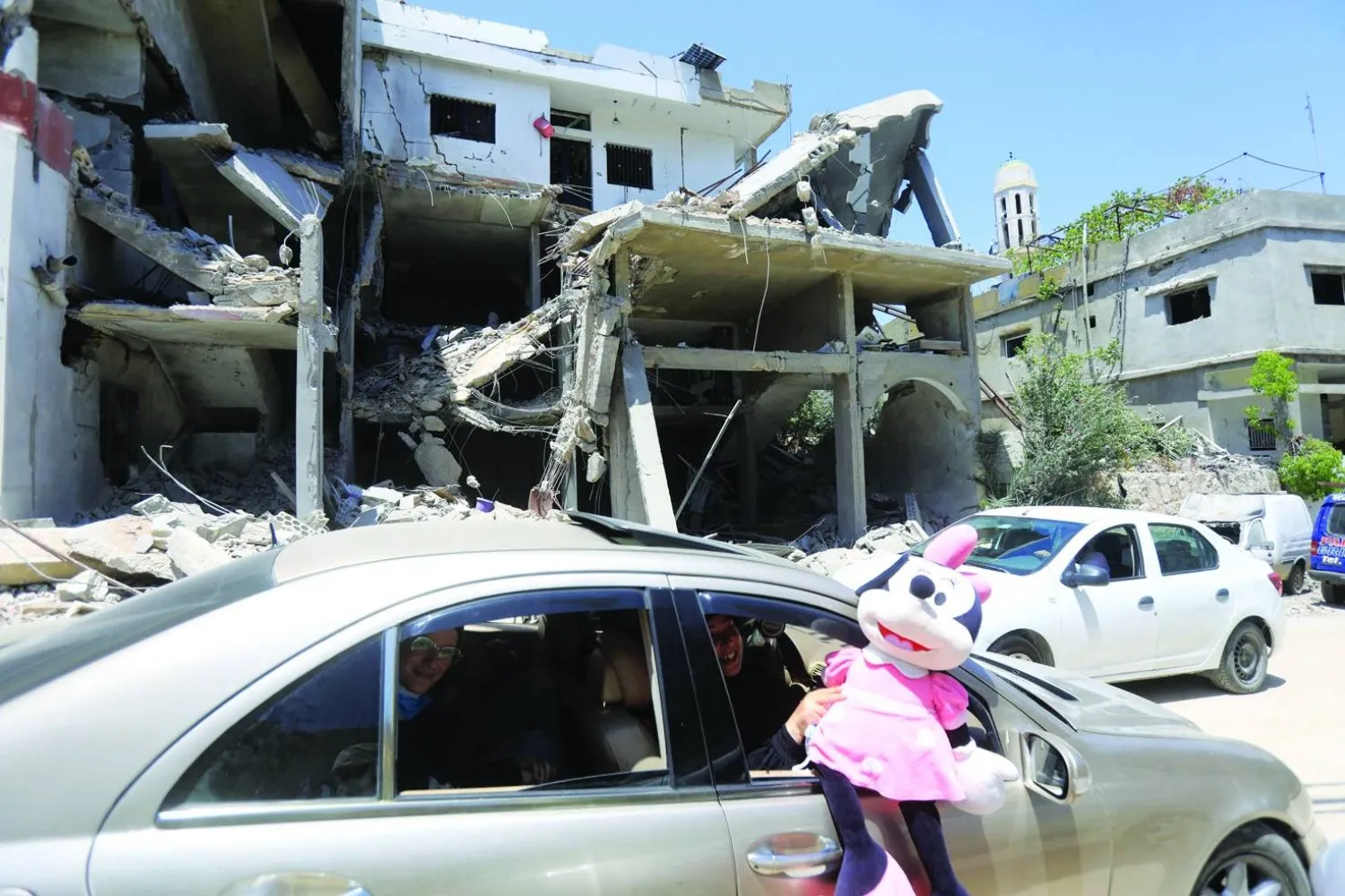 Lübnan'ın güneyindeki Ayta eş-Şaab kasabasında İsrail bombardımanında yıkılan bir evin önünden geçen kadın elinde oyuncak bebek tutuyor. (AFP)