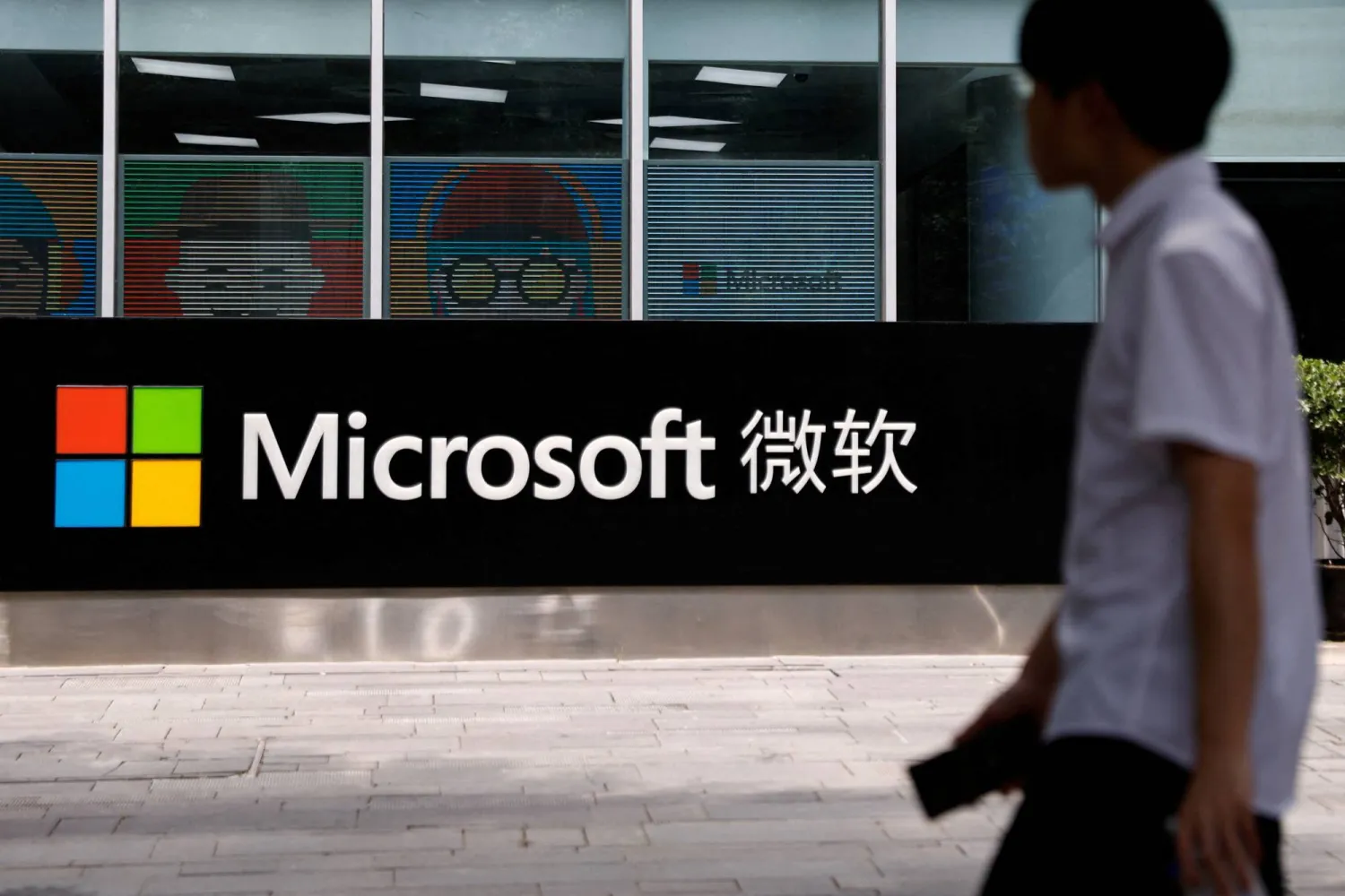 FILE PHOTO: A person walks past a Microsoft sign at its office building in Beijing, China May 25, 2023. REUTERS/Tingshu Wang/File Photo