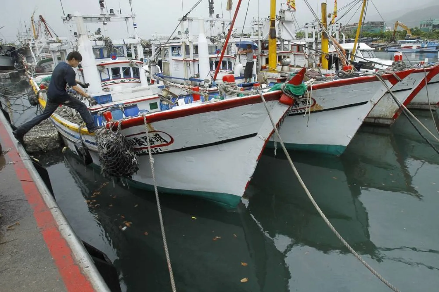A fisherman leaps to his boat docked in harbor in Toucheng, north eastern Taiwan, Aug. 21, 2013. (AP)