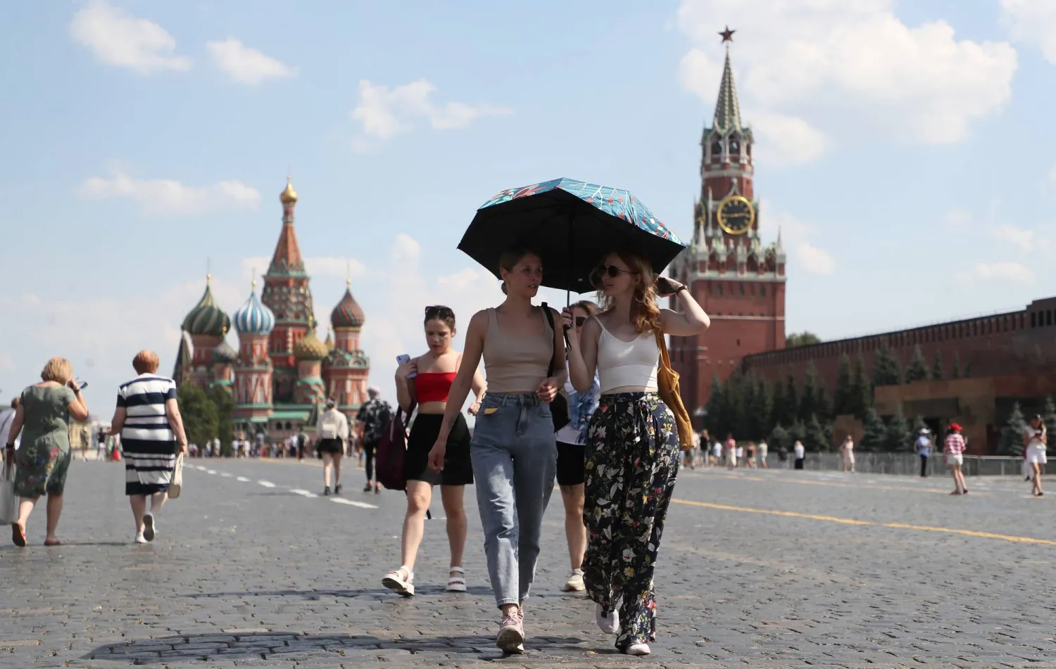 People walk on the Red Square outside the Kremlin in Moscow, Russia, 02 July 2024. The temperature in Moscow exceeded 32 degrees Celsius. EPA/MAXIM SHIPENKOV