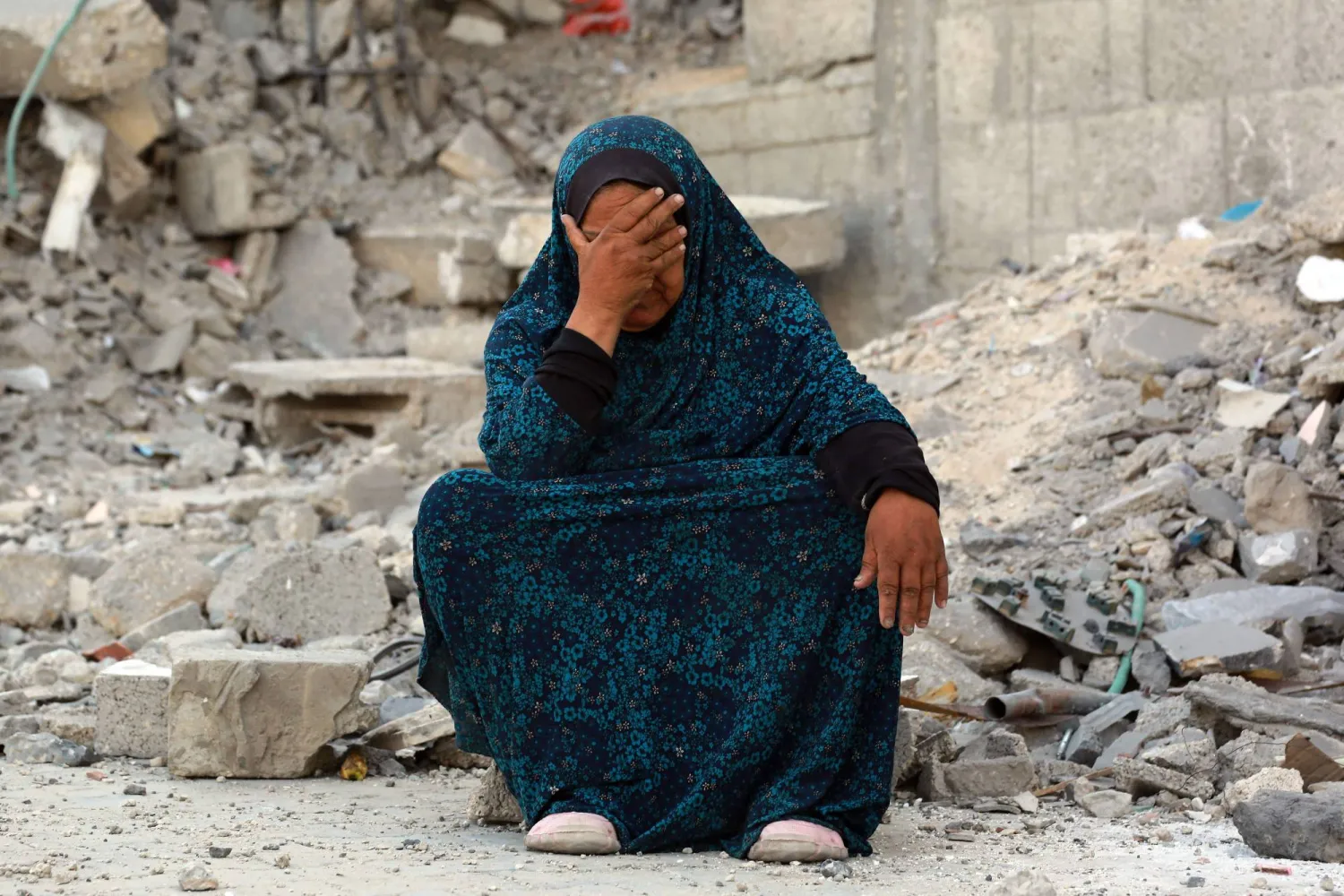 سيدة فقدت معظم عائلتها تجلس باكية وسط حطام منزلها في خان يونس (أ.ف.ب)