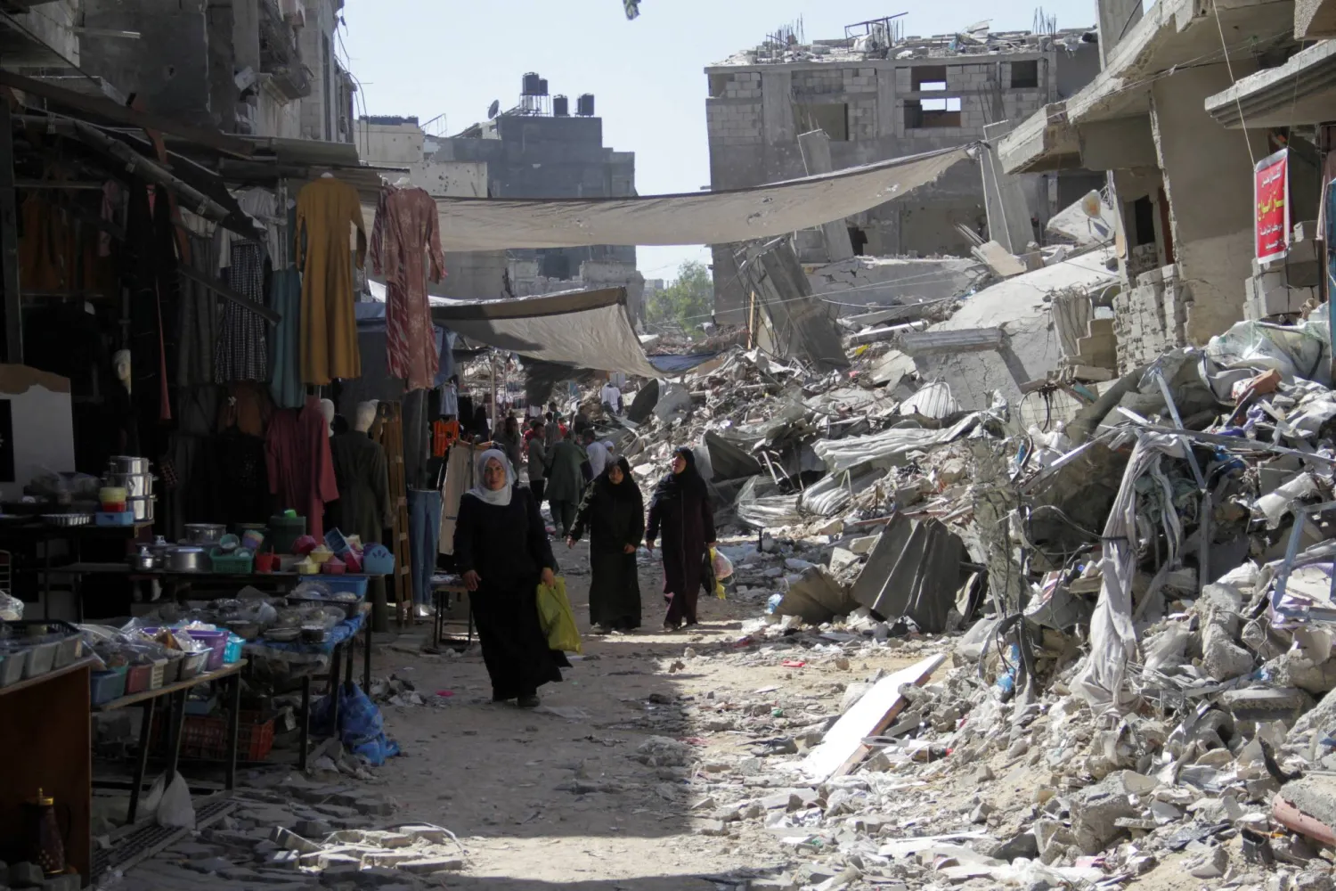 FILE PHOTO: Palestinians walk near houses destroyed in the Israeli military offensive as they struggle with food scarcity, basic necessities amid the conflict between Israel and Hamas continues, in Jabalia refugee camp, in the northern Gaza Strip, June 19, 2024. REUTERS/Mahmoud Issa/File Photo