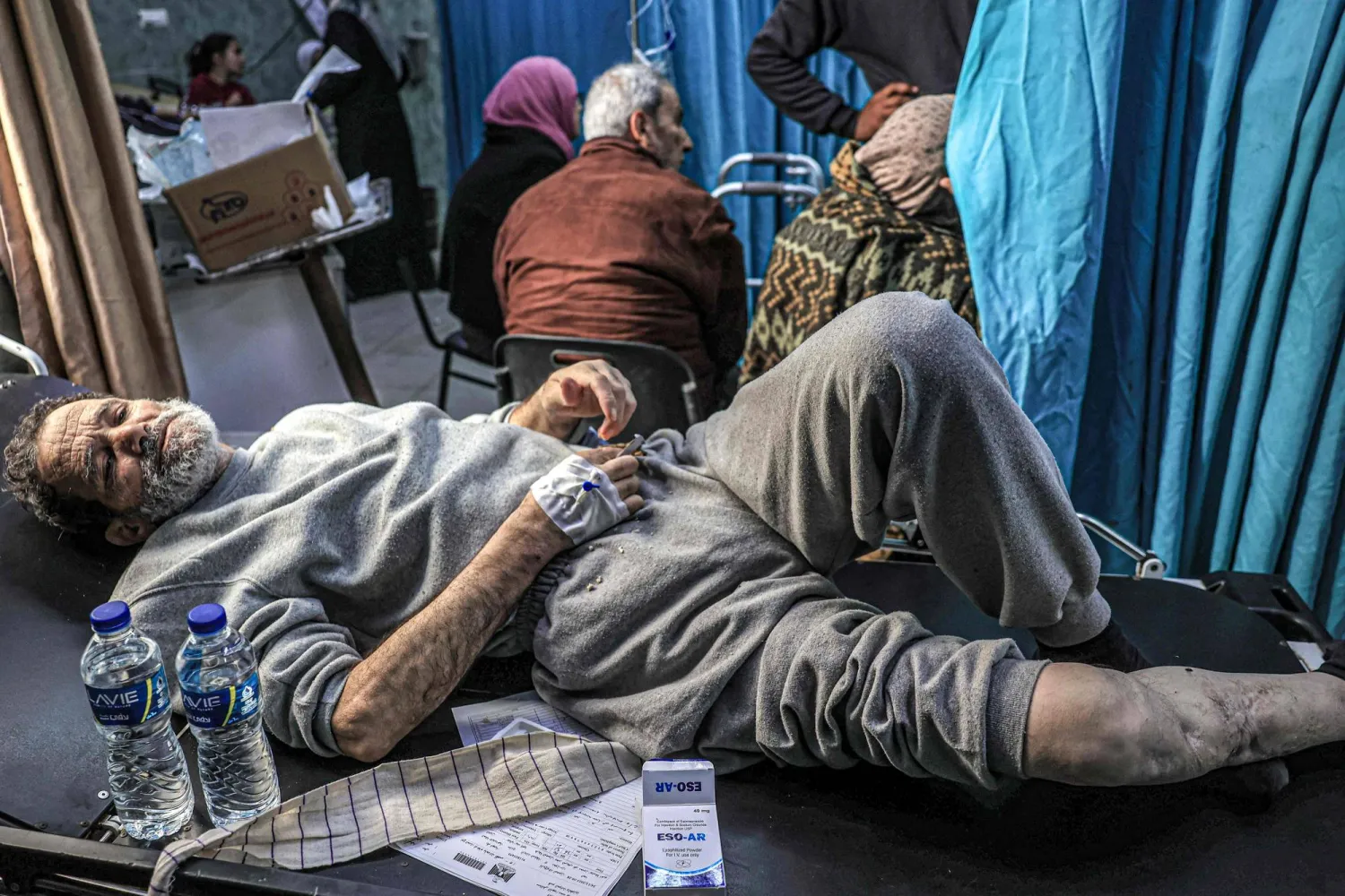 رجال مصابون كانوا من بين الفلسطينيين الذين اعتقلهم الجيش الإسرائيلي خلال عمليته في شمال قطاع غزة وأفرج عنهم مؤخراً عبر معبر كرم أبو سالم ينتظرون العلاج لإصاباتهم في مستشفى النجار في رفح جنوب قطاع غزة - 24 ديسمبر 2023 (أ.ف.ب)