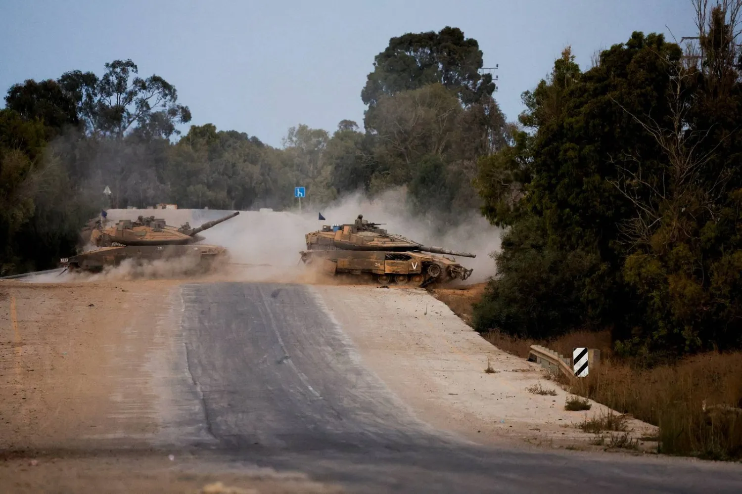 دبابتان إسرائيليتان تعبران طريقاً بالقرب من الحدود بين إسرائيل وغزة (رويترز)