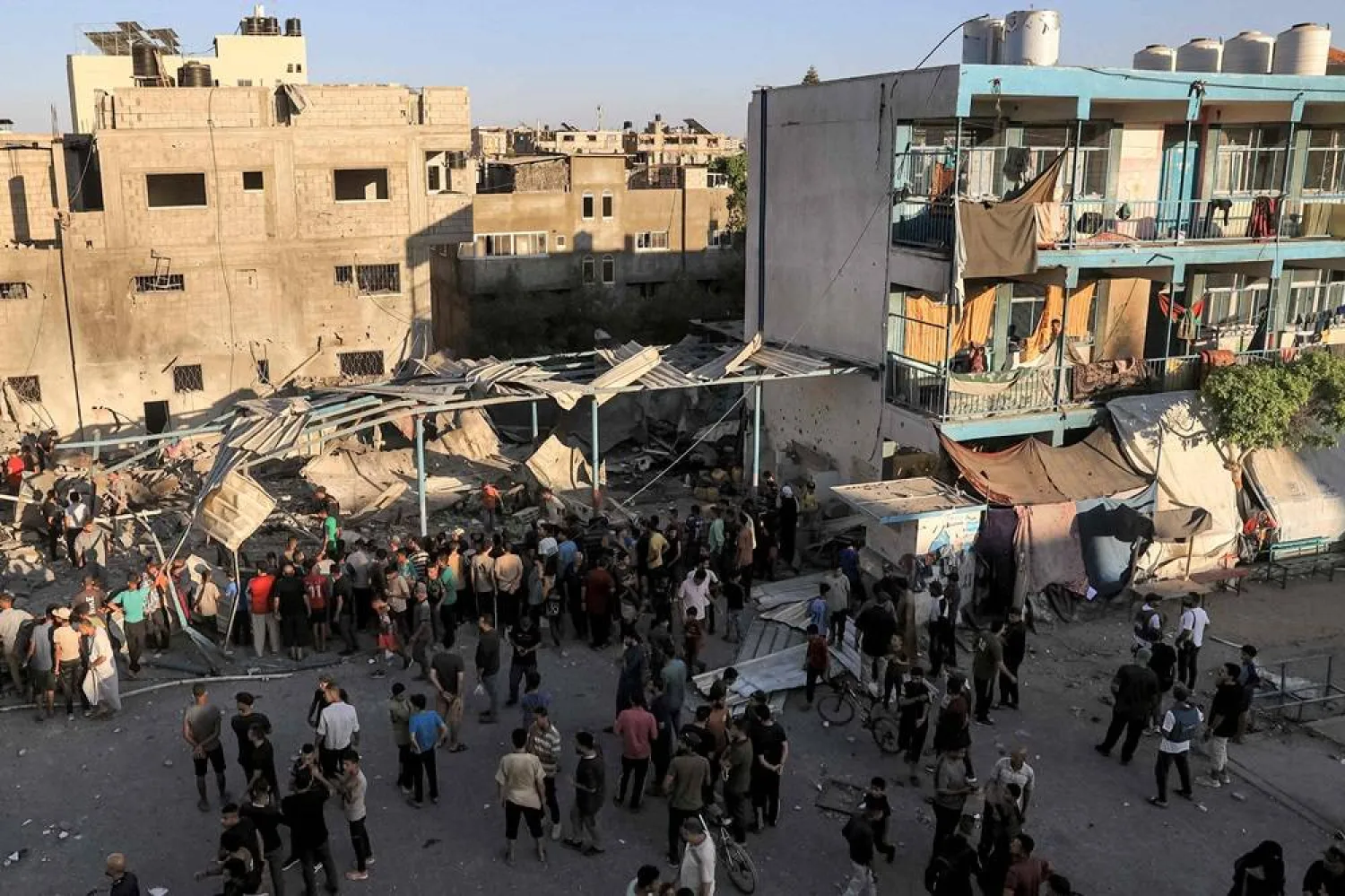 People gather to search the rubble of a collapsed building in the aftermath of Israeli bombardment at the Jaouni school run by the UN Relief and Works Agency for Palestine Refugees (UNRWA) in Nuseirat in the central Gaza Strip on July 6, 2024 amid the ongoing conflict in the Palestinian territory between Israel and Hamas. (AFP)