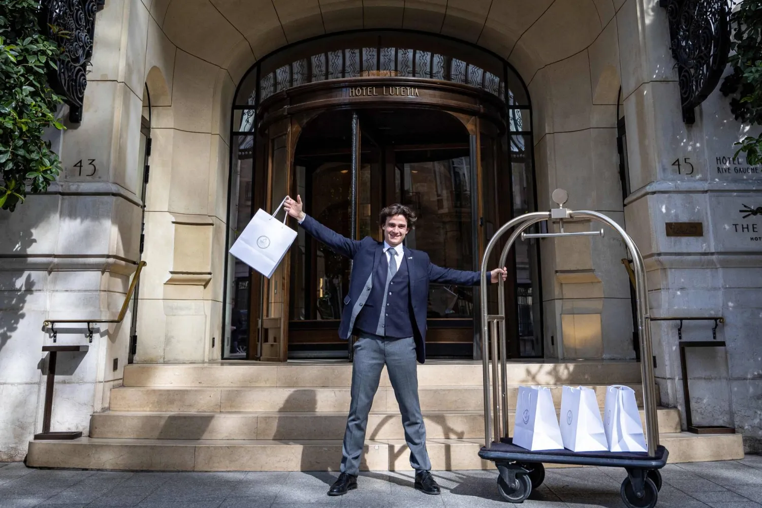 جان عامل في فندق «لوتيتيا» يقف أمامه مبتسماً في باريس (أ.ف.ب)