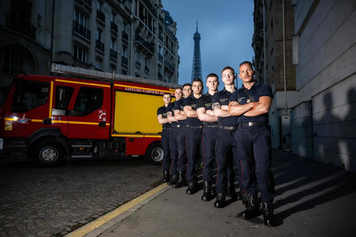 أعضاء من فرقة إطفاء باريس يقفون أمام شاحنتهم (أ.ف.ب)