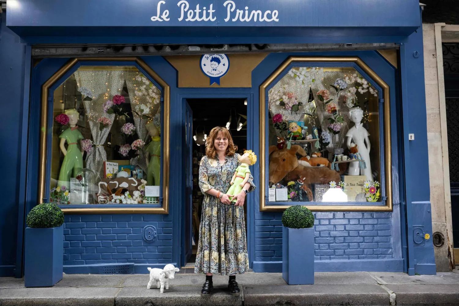 أوريليا مديرة متجر «Le Petit Prince» في باريس تقف وهي تحمل دمية لشخصية «Le Petit Prince» من كتاب «الأمير الصغير» (أ.ف.ب)