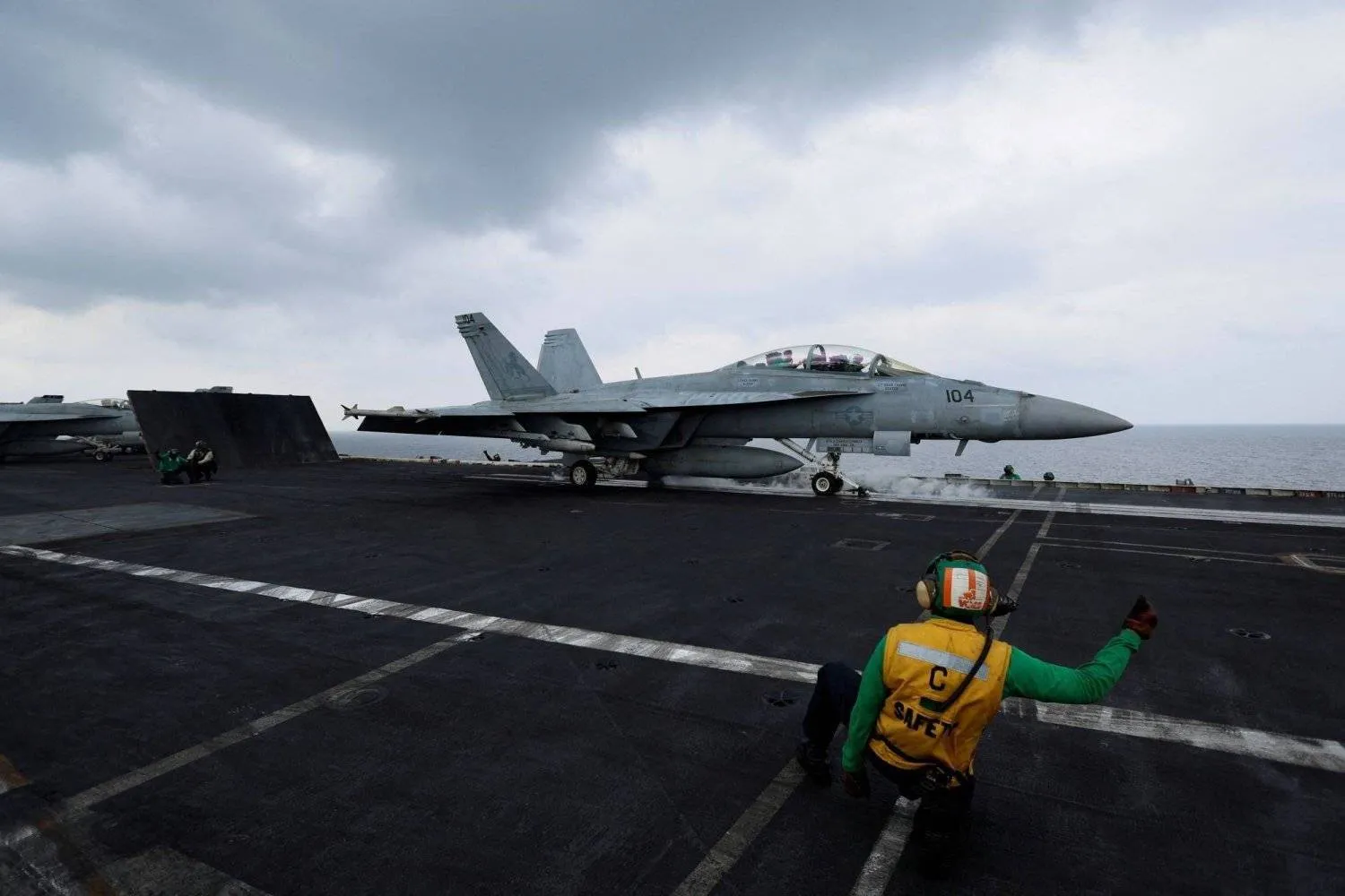 A flight operating crew member signals a F/A-18E Super Hornet fighter jet on the flight deck of the USS Dwight D. Eisenhower (CVN 69) aircraft carrier in Southern Red Sea, Middle East, February 13, 2024. Reuters