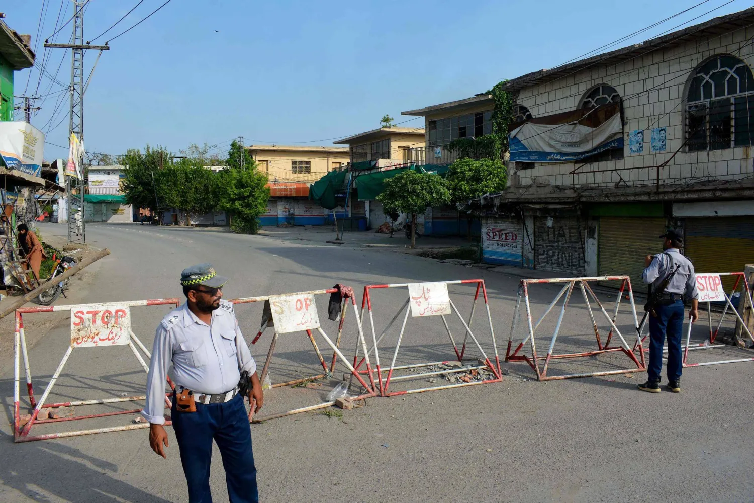 Policemen stand guard along a barricaded street near an army cantonment, a day after it was attacked by a militant suicide squad in Bannu on July 16, 2024. (Photo by Karim ULLAH / AFP)