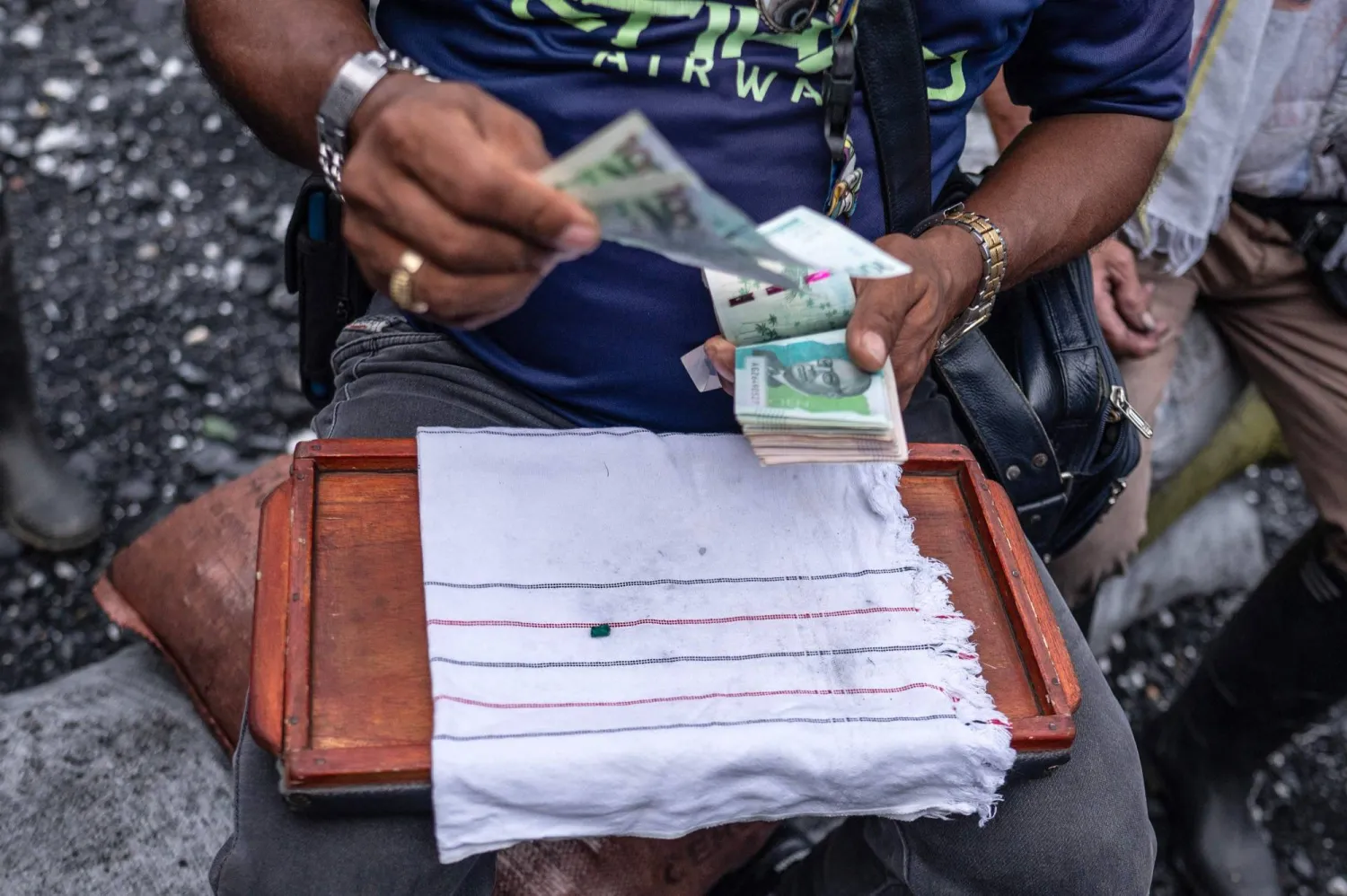 رجل يحمل فئات نقدية لحساب العمال الباحثين عن الزمرد بالقرب من نهر لاس أنيماس في موزو بمقاطعة بوياكا (أ.ف.ب)