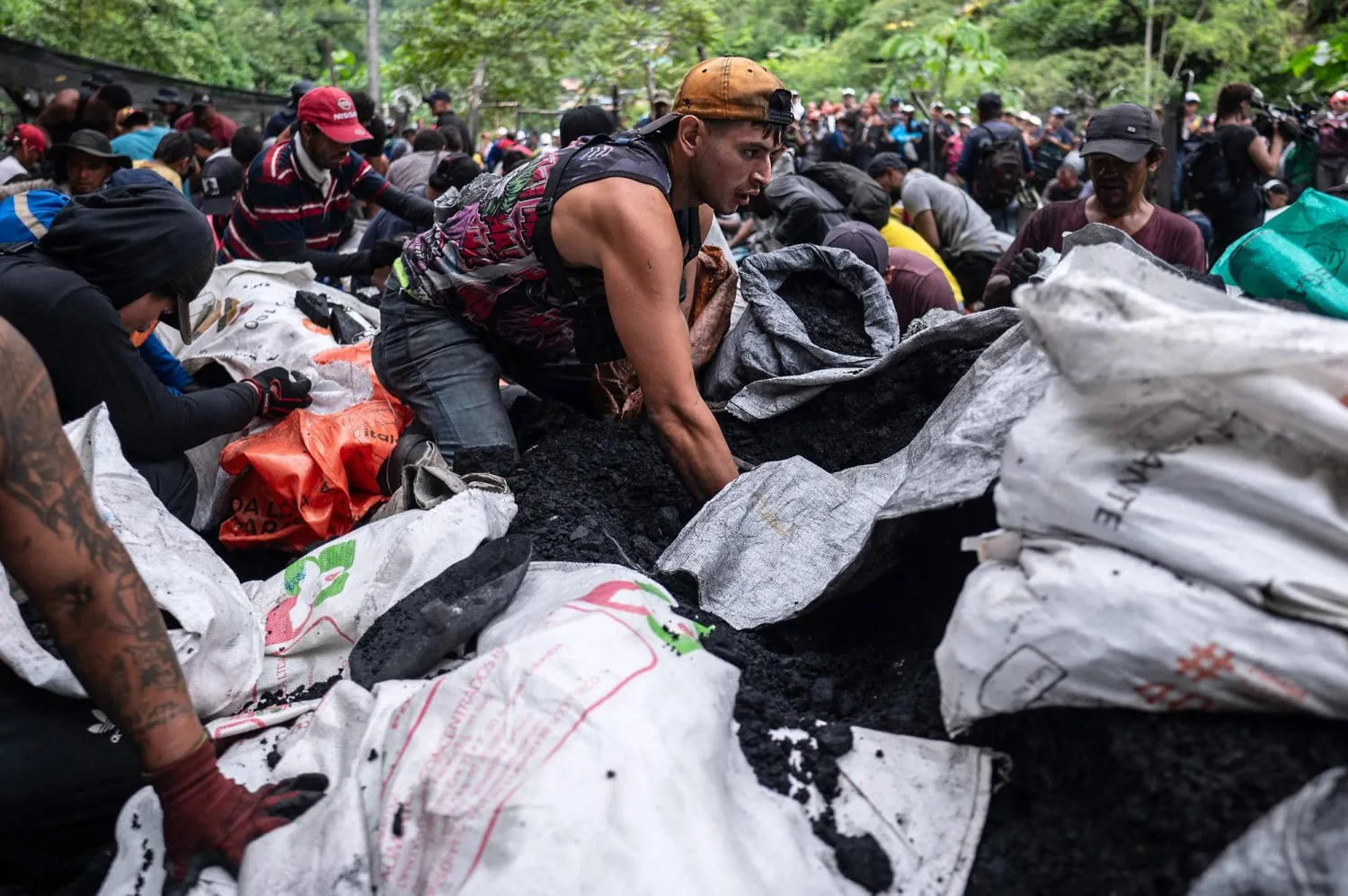 العمال يرصون أكياس التربة لغسلها وغربلتها بحثاً عن الزمرد (أ.ف.ب)