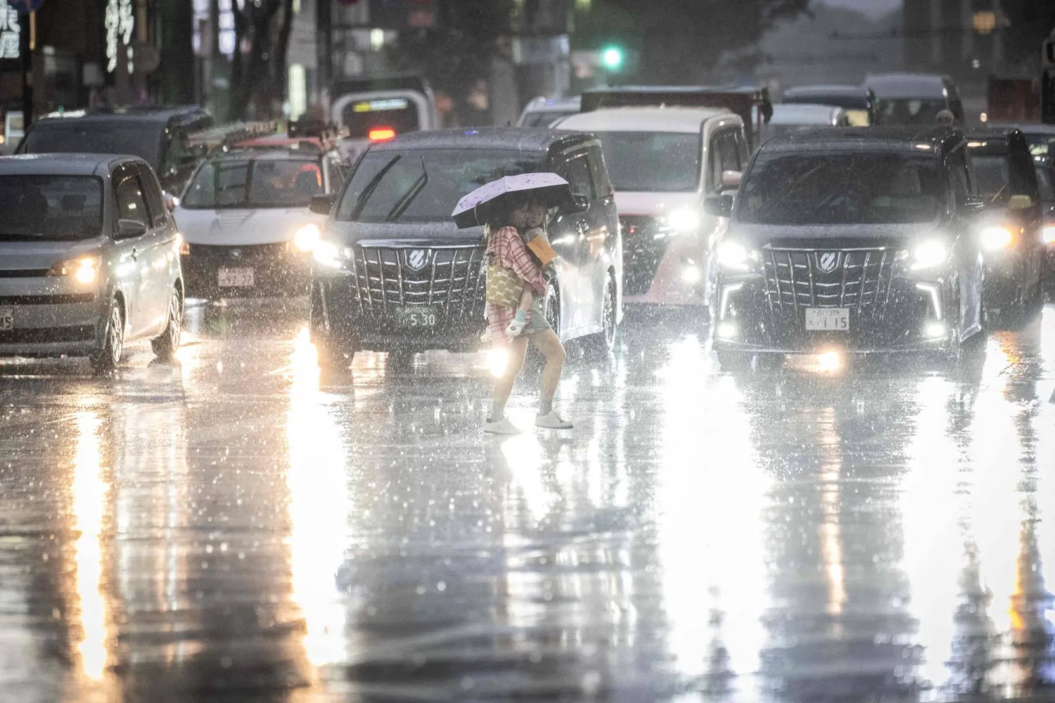 سيدة تعبر الطريق في العاصمة اليابانية طوكيو تحت أمطار غزيرة (أ.ف.ب)