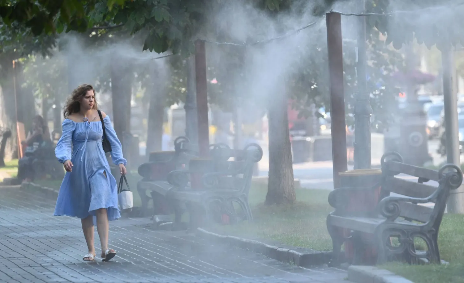 سيدة تسير بالقرب من نافورة المياه لتهون حرارة الطقس في كييف (أ.ف.ب)