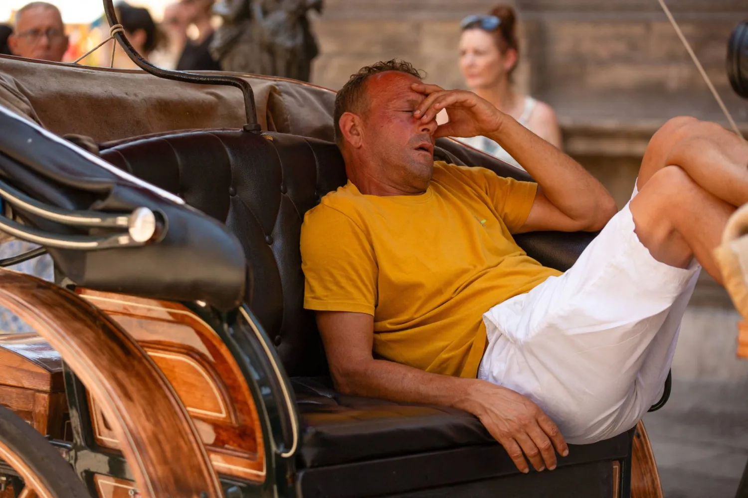 رجل يجلس في الجزء الخلفي من عربة تجرها الخيول خلال موجة حارة في باليرمو عاصمة جزيرة صقلية الإيطالية (رويترز)