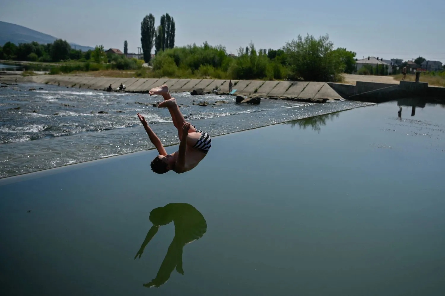 صبي يقفز في نهر إيبر ليبرد في ميتروفيتشا حيث وصلت درجة الحرارة إلى 40 درجة مئوية (أ.ف.ب)