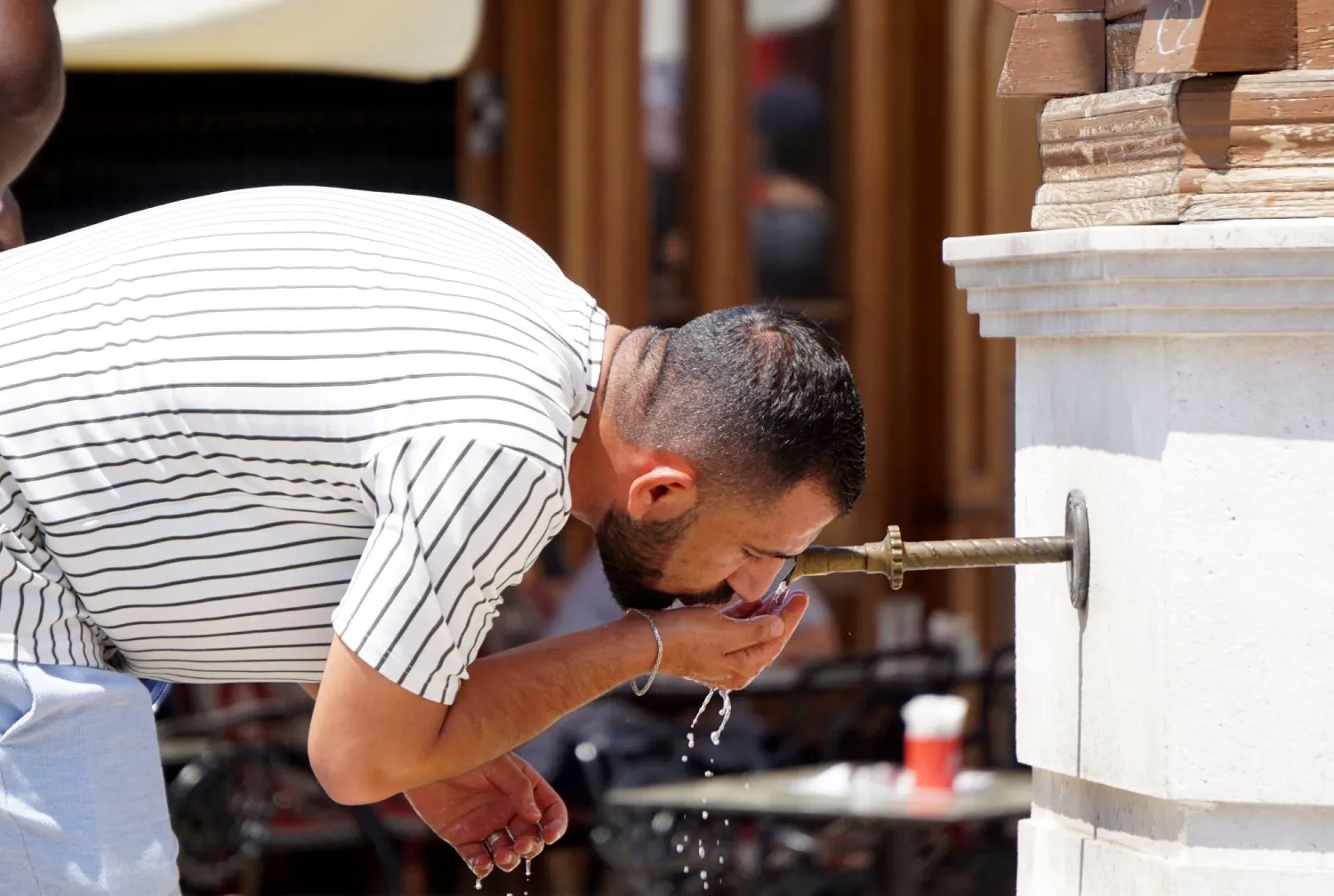 رجل يشرب الماء من حنفيات عامة حول مركز سراييفو التاريخي «باسكارسييا» (أ.ف.ب)