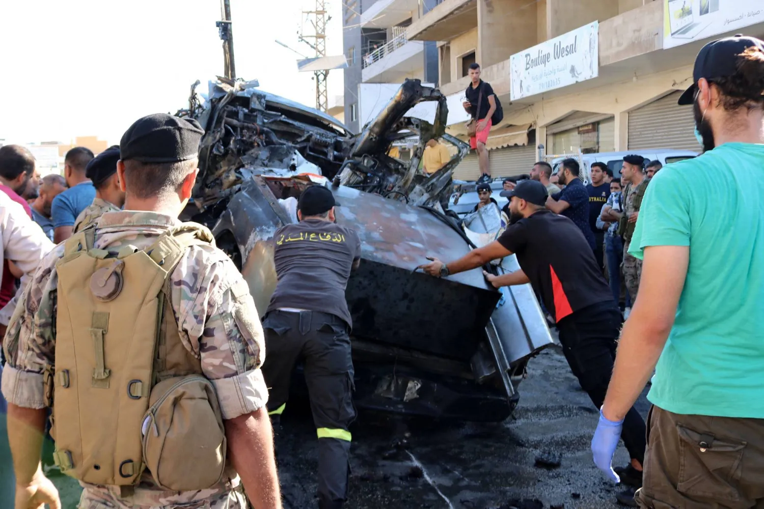 مواطنون لبنانيون يرفعون أنقاض سيارة قيادي في «الجماعة الإسلامية» استهدفته إسرائيل بشرق لبنان (أ.ف.ب)