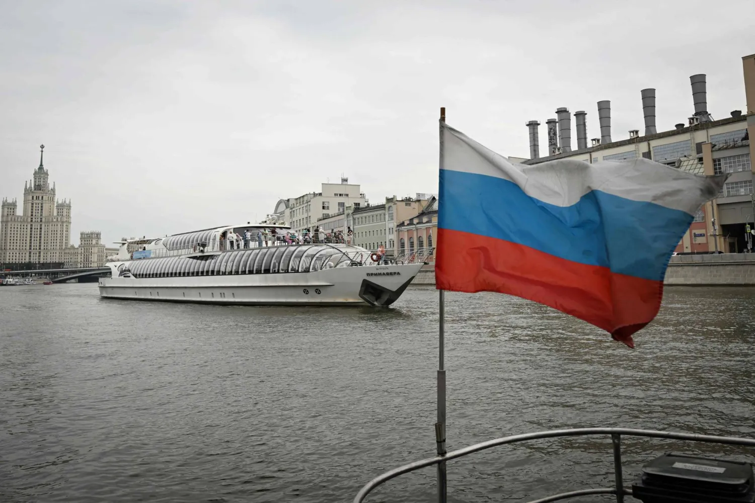 A Russian national tricolor flag flutters on a tourist boat as another boat passes by along the Moskva river in central Moscow on July 18, 2024. (Photo by Natalia KOLESNIKOVA / AFP)