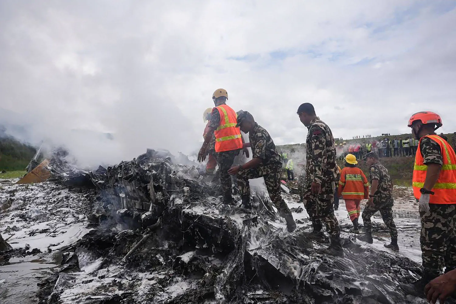 Rescuers and army personnel stand at the site after a Saurya Airlines' plane crashed during takeoff at Tribhuvan International Airport in Kathmandu on July 24, 2024. (Photo by Prabin RANABHAT / AFP)