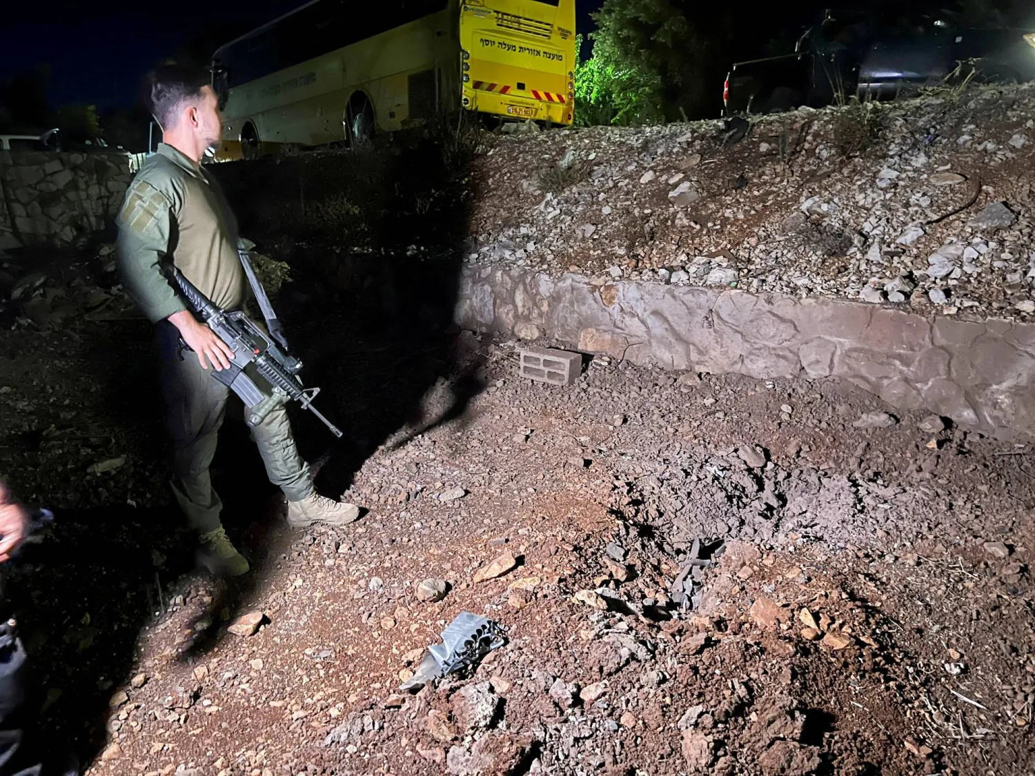 جندي إسرائيلي يقف بالقرب من بقايا صاروخ أُطلق من لبنان (رويترز)