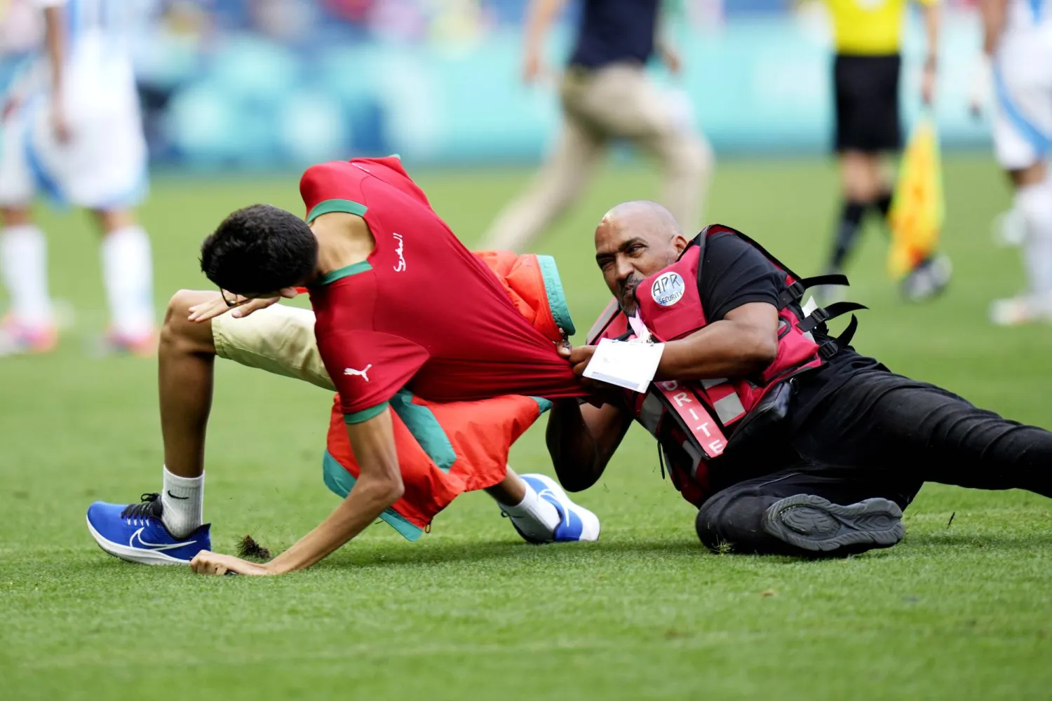 رجل أمن في محاولة الإمساك بأحد الجماهير المقتحمين لملعب المباراة (أ.ب)