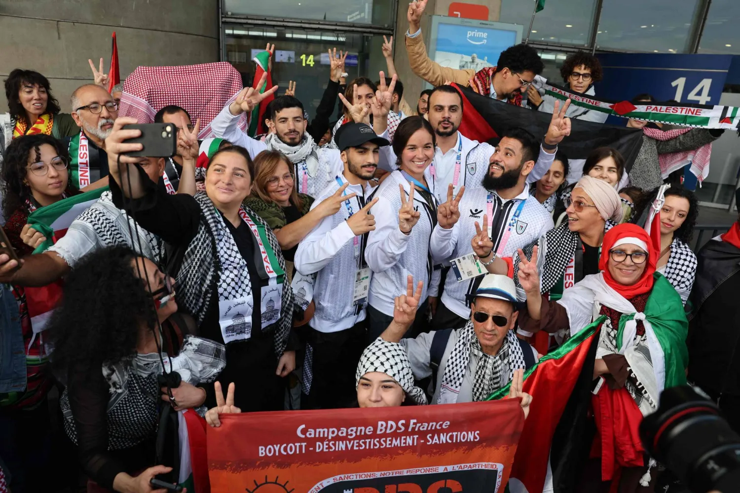 الرياضيون الأولمبيون الفلسطينيون وأعضاء الوفد يقفون مع أنصارهم لدى وصولهم إلى مطار شارل ديغول في باريس (أ.ف.ب)