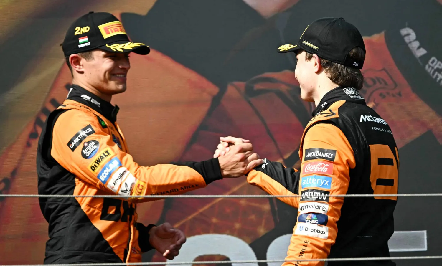 نوريس (يسار) يصافح زميله في الفريق أوسكار بياستري (يمين)... (أ.ف.ب)