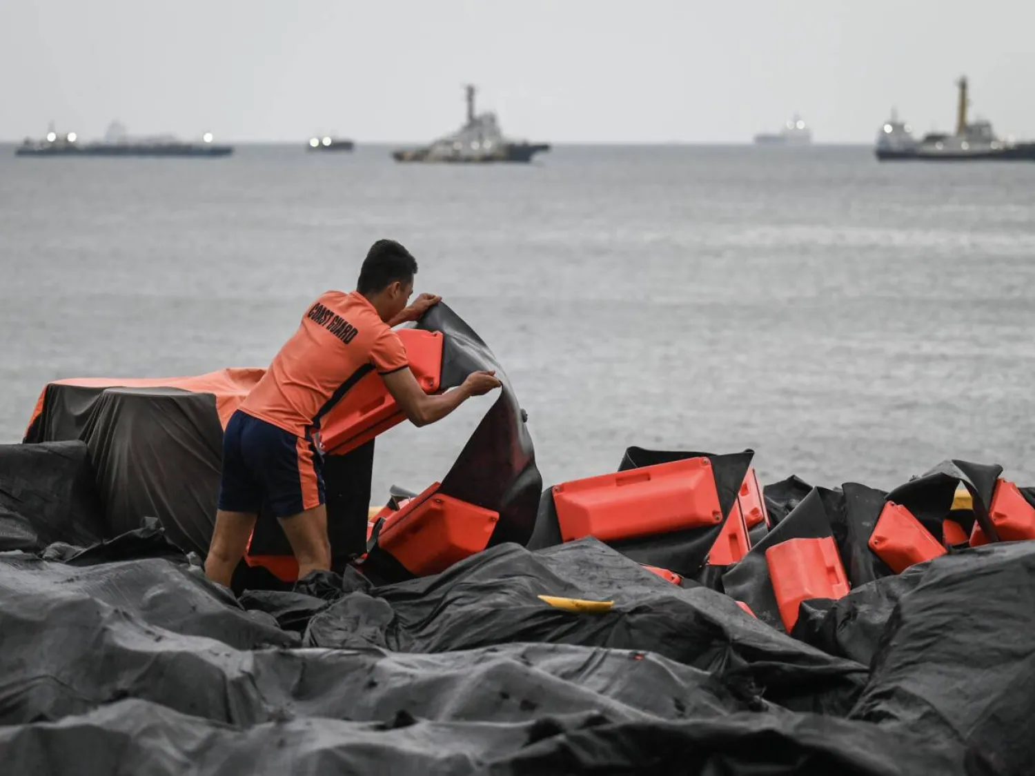 A coast guard staffer arranges an oil spill containment boom to be use3d in Manila Bay. Jam Sta Rosa / AFP

