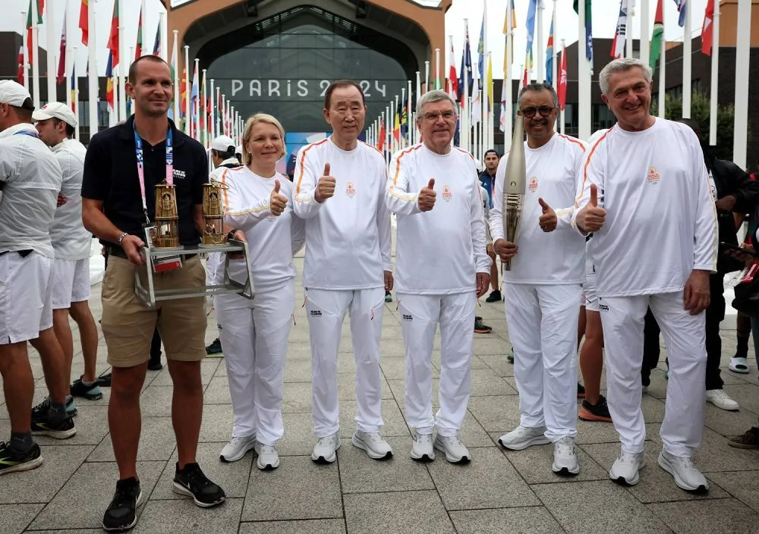 Paris 2024 Olympics - Olympic Village Torch Relay - Olympic Village, Paris, France - July 26, 2024. Matthieu Garel, Emma Terho, Chair of the IOC Athletes' Commission, Ban Ki-moon, former Secretary-General of the United Nations, Thomas Bach, President of the International Olympic Committee (IOC), Tedros Adhanom Ghebreyesus, Director-General of the World Health Organization and Filippo Grandi, Commissioner of the United Nations High Commissioner for Refugees pose before the Olympic Village Torch Relay. (Reuters) 