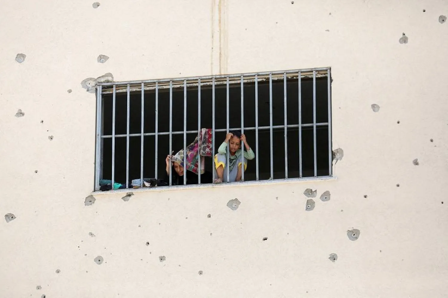Displaced Palestinians, who fled their houses due to Israeli strikes, look out from a window as they take shelter, amid the ongoing conflict between Israel and Hamas, in Khan Younis in the southern Gaza Strip, July 24, 2024. (Reuters) 